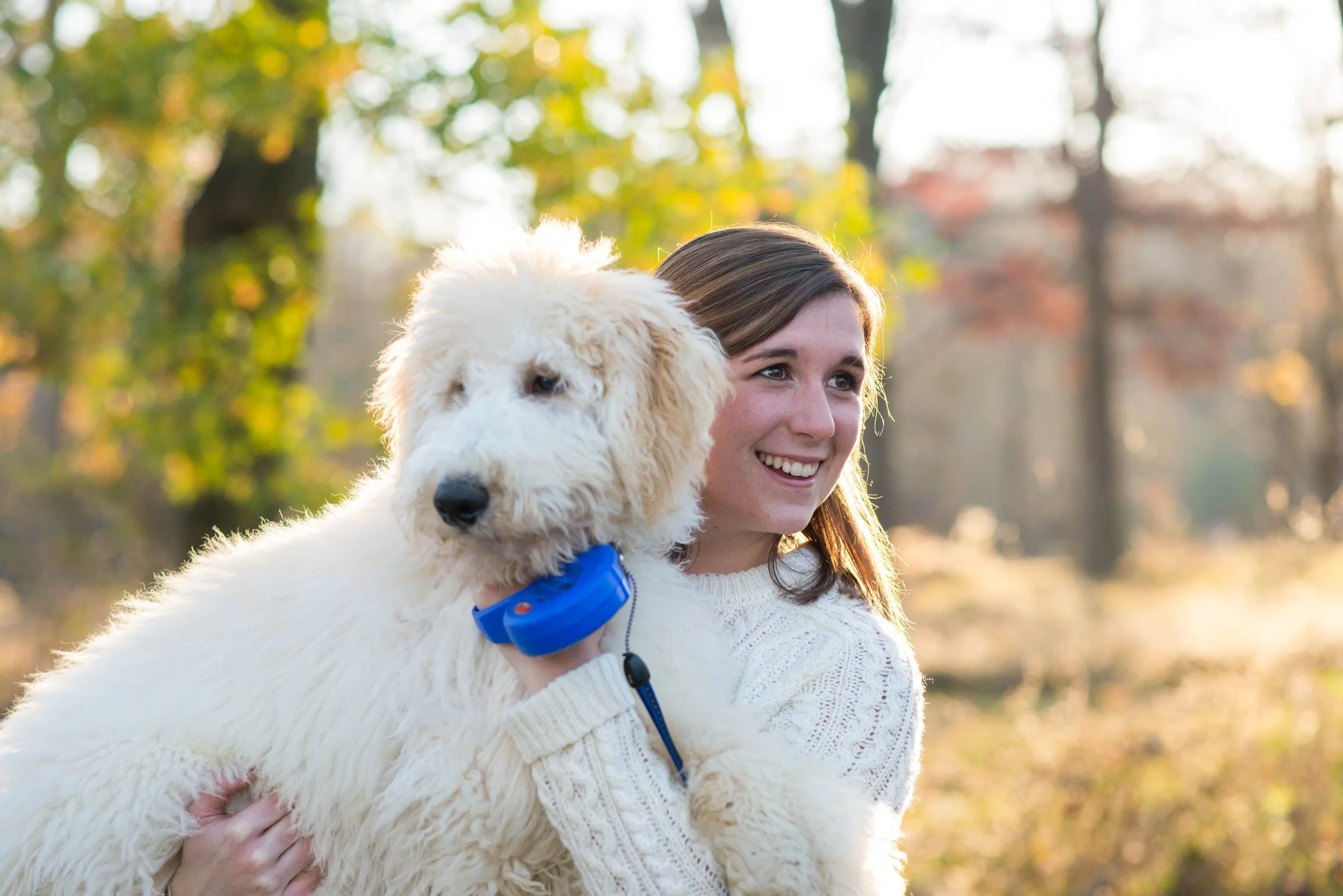 A woman holds up her shaggy dog during her engagement photos