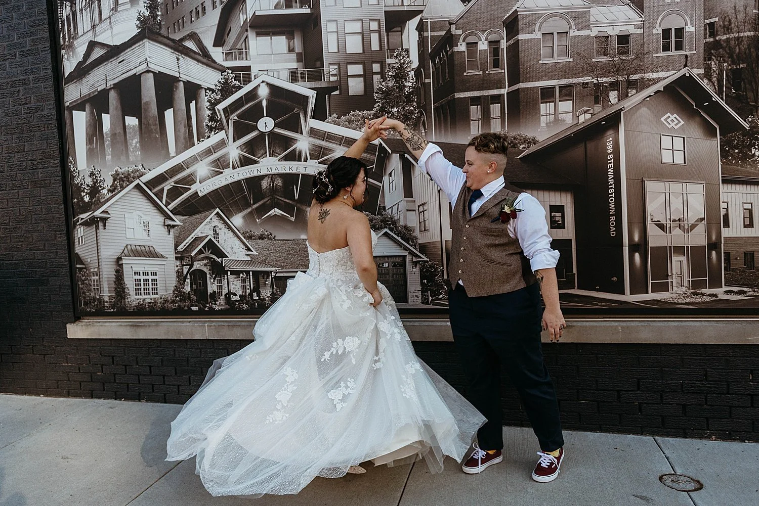 Groom twirls the bride in front of a mural, her dress spins out around her