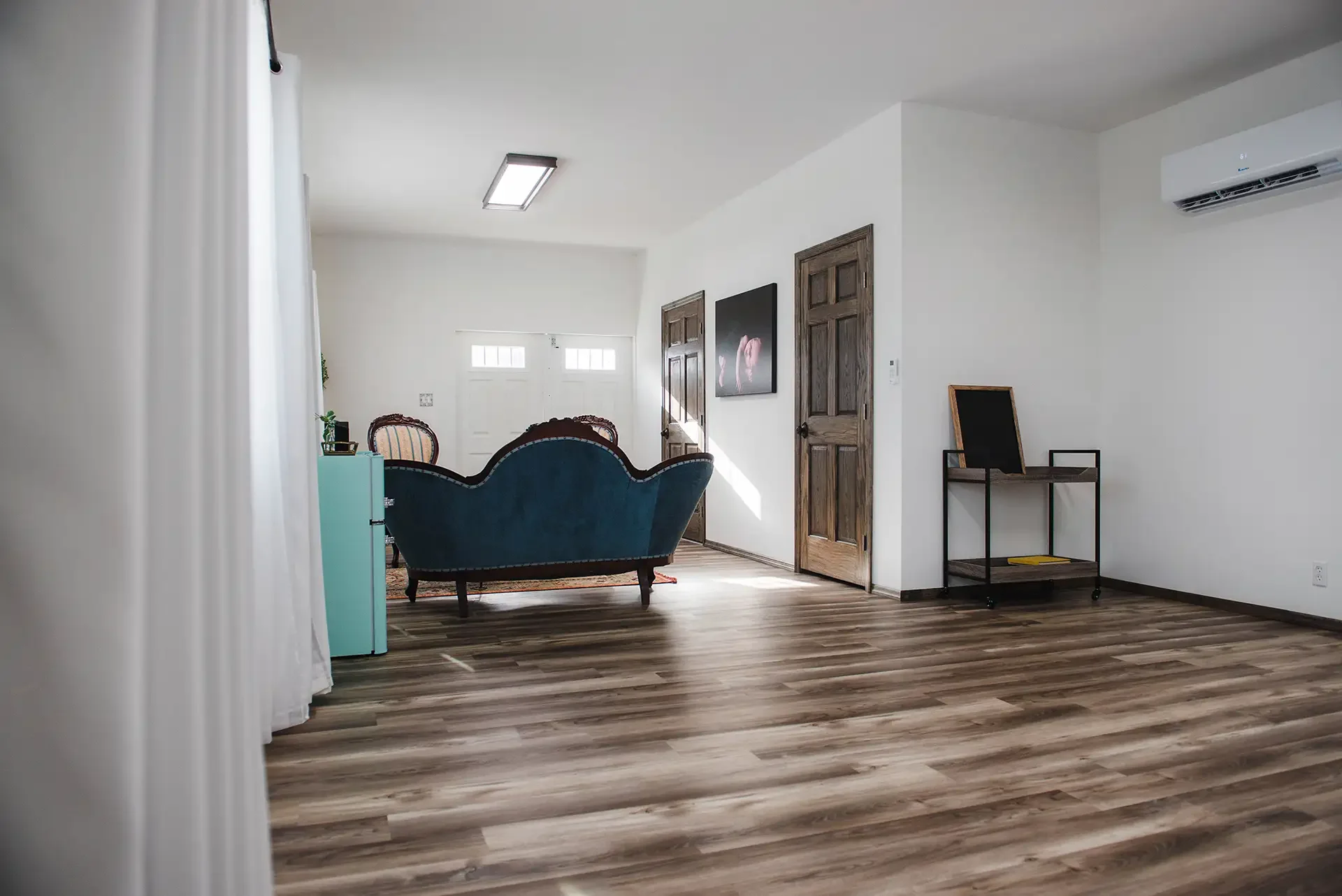 another wide shot of the studio space, showing the back of the couch and the doors to the closet and bathroom