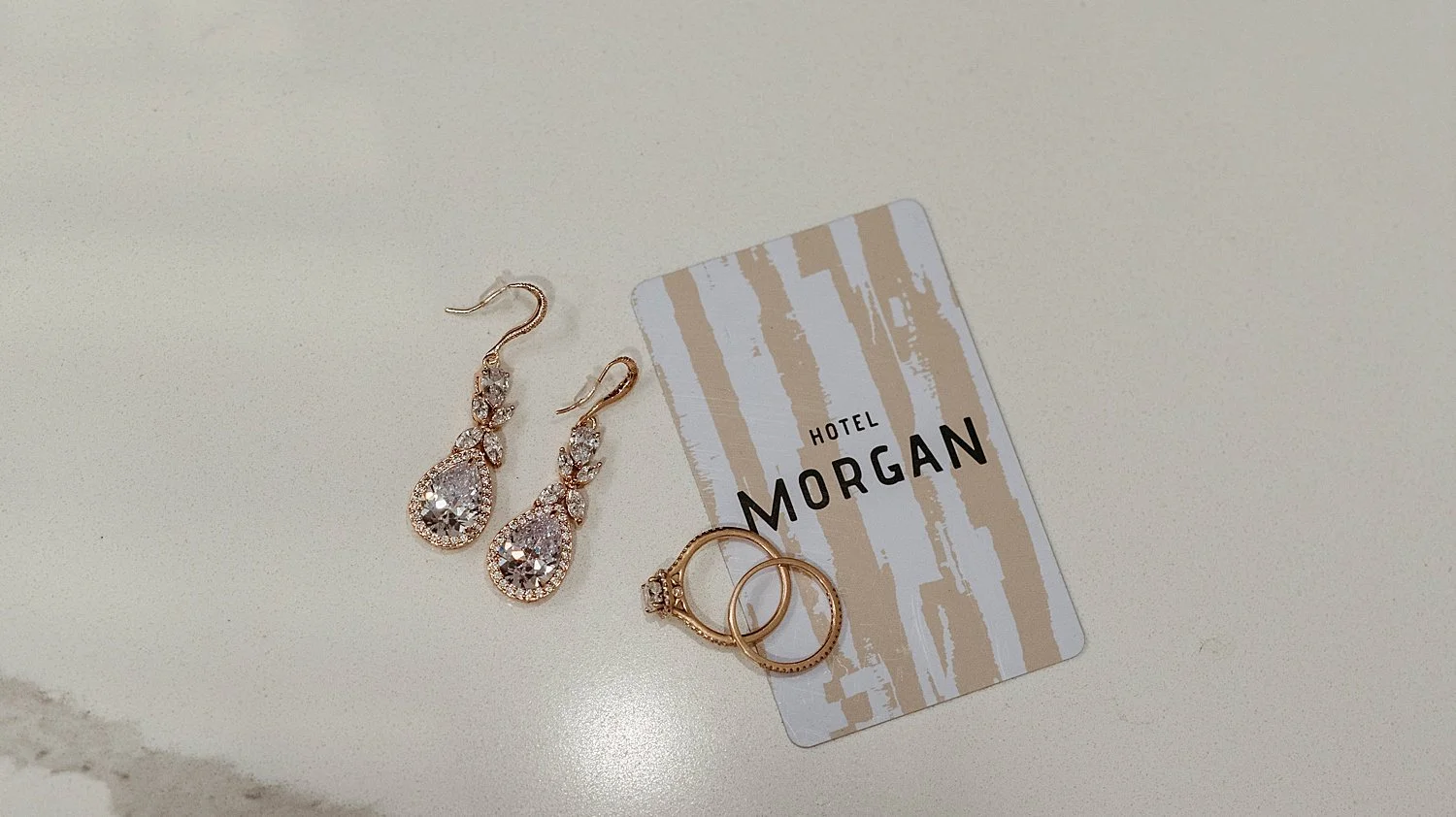 detail shot of earrings, rings, and a hotel morgan room key card