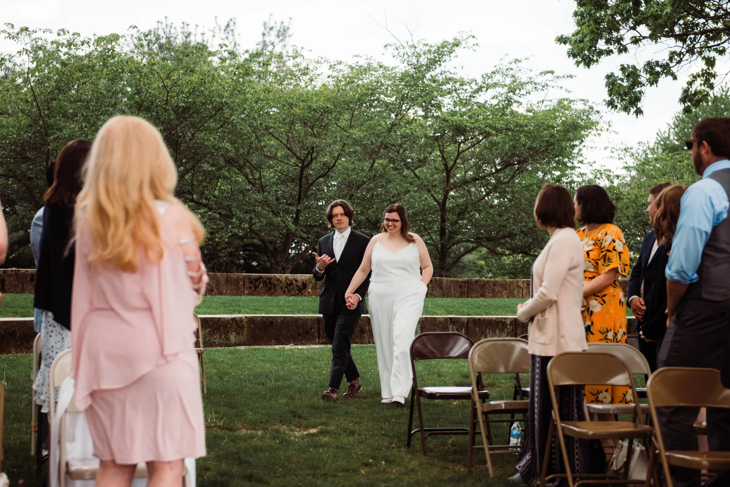Bride and groom walk down the aisle at West End Overlook, groom is doing the hang ten hand motion