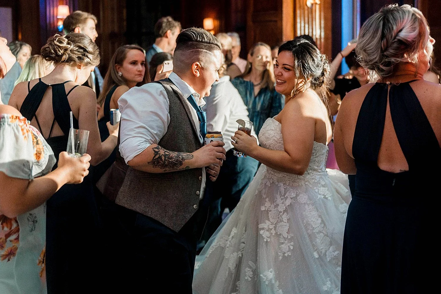 Bride and groom are dancing close together at the reception, groom is holding a drink