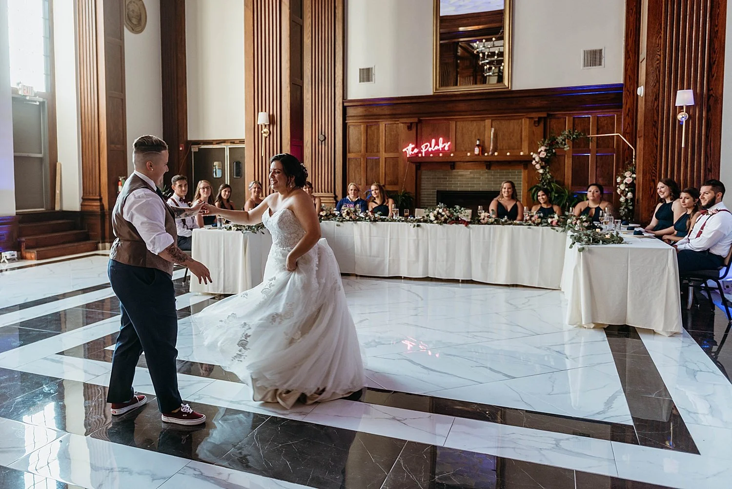 bride and groom dance in front of tables of their wedding party