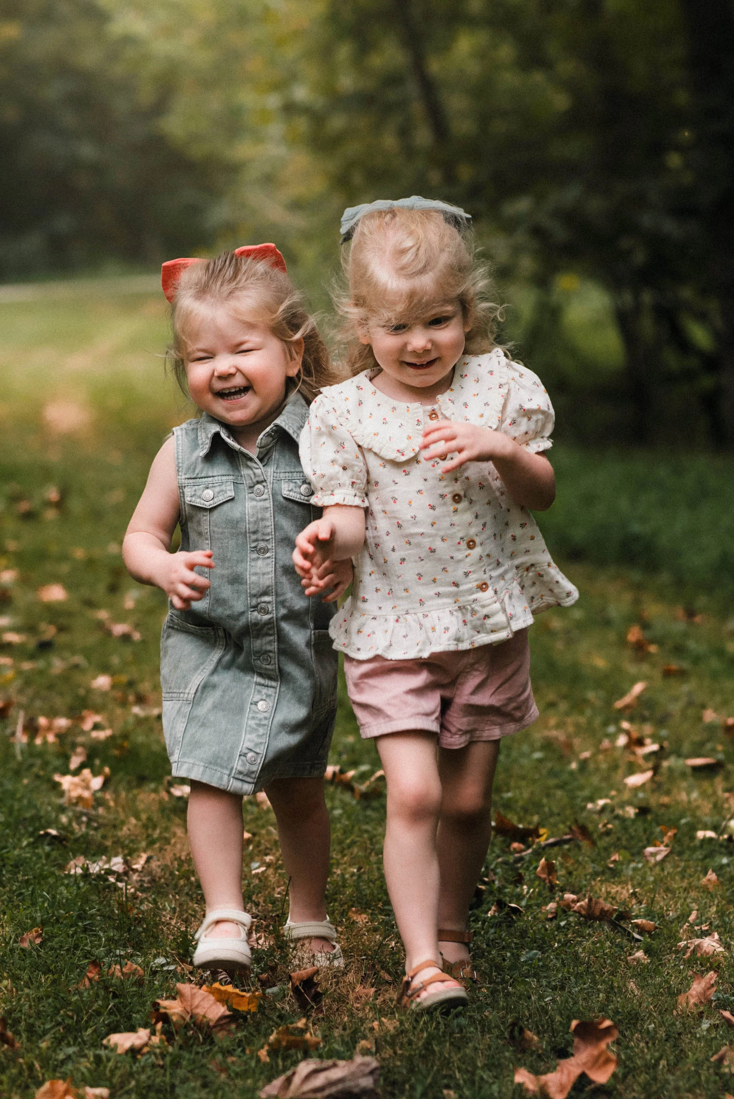 two young blonde girls holding hands in the park and smiling at cedar creek, pa
