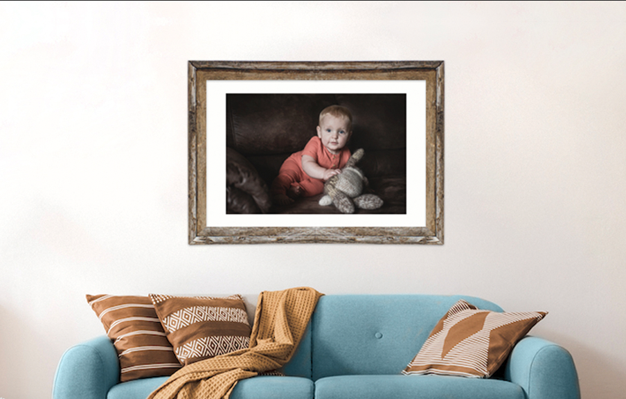 framed portrait of a baby above a couch