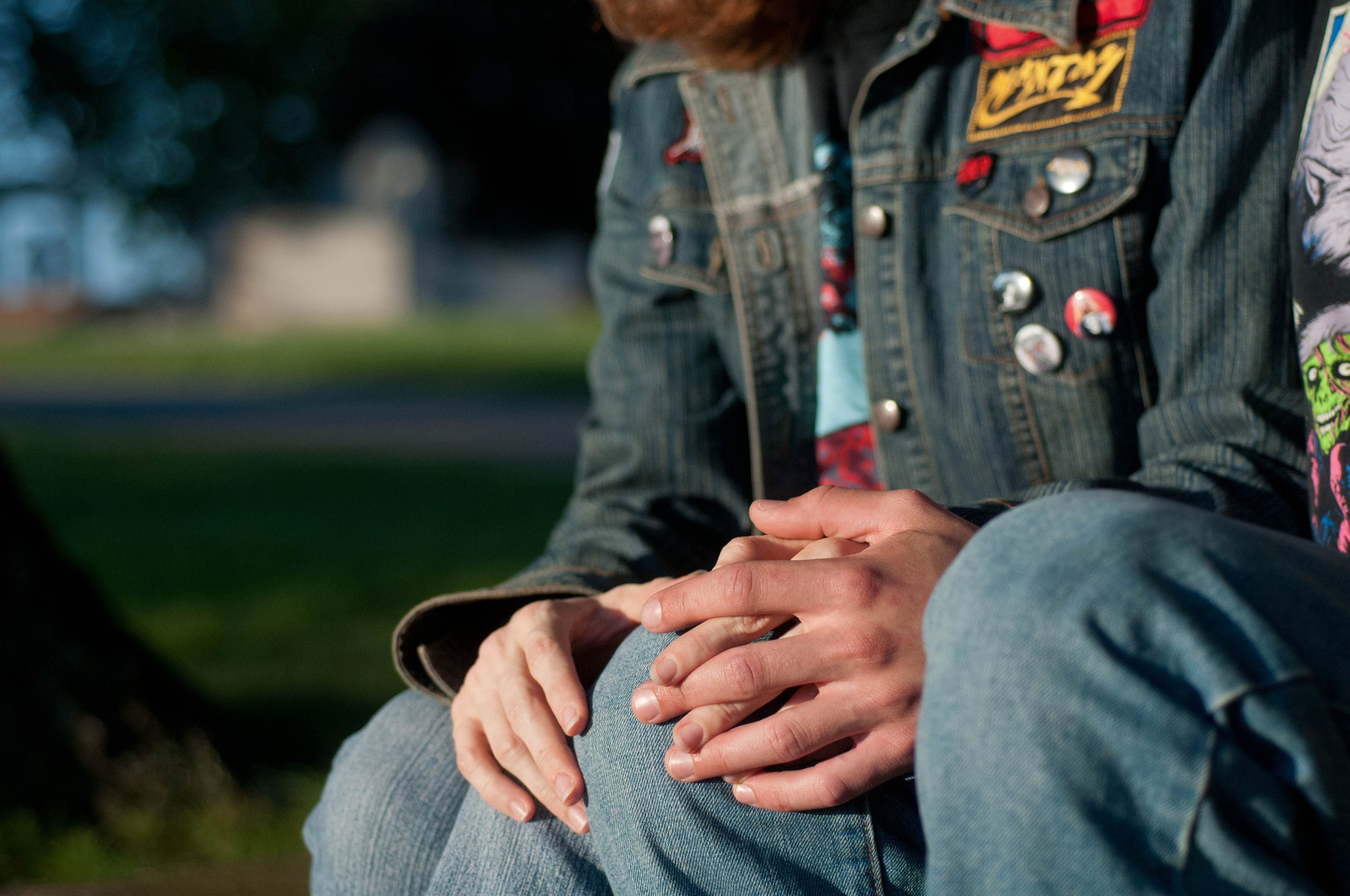 Close up of couple holding hands, they are wearing band tshirts and battle vests with punk and hardcore pins