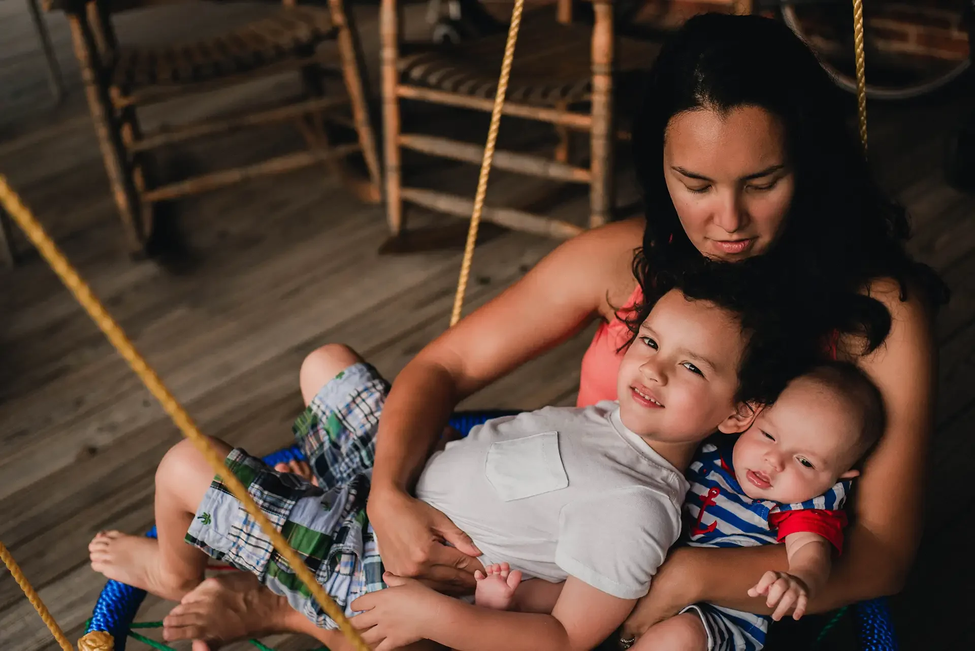 A mother holds her toddler and baby in a swing