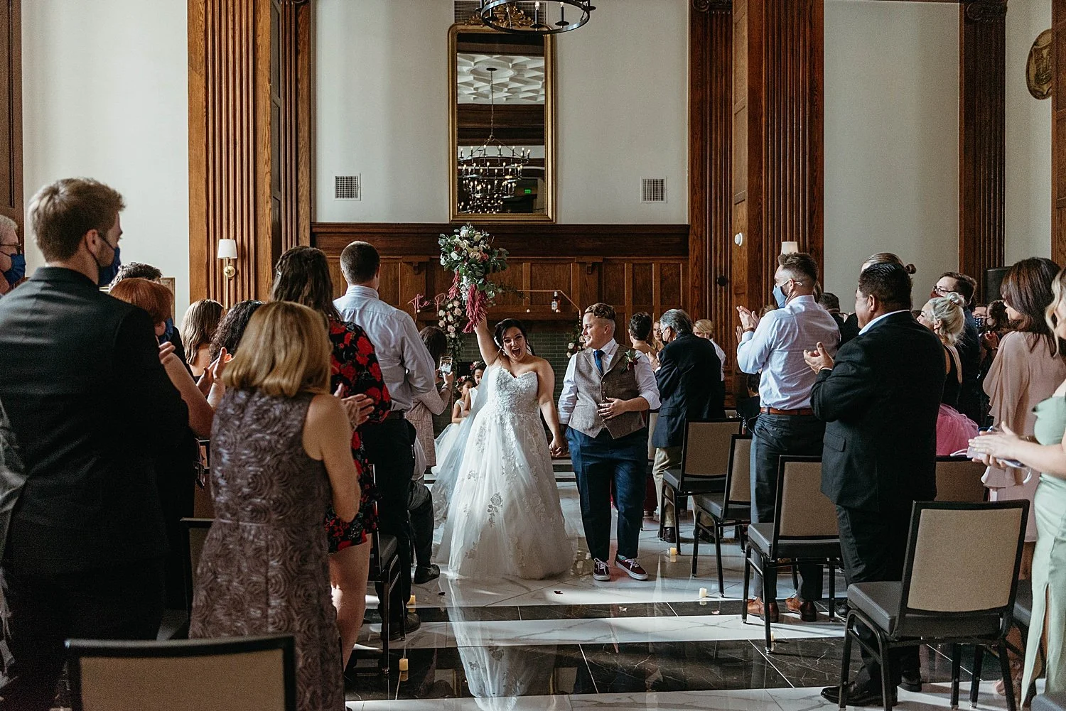 Recessional of the wedding. The bride holds her bouqet high in the air.