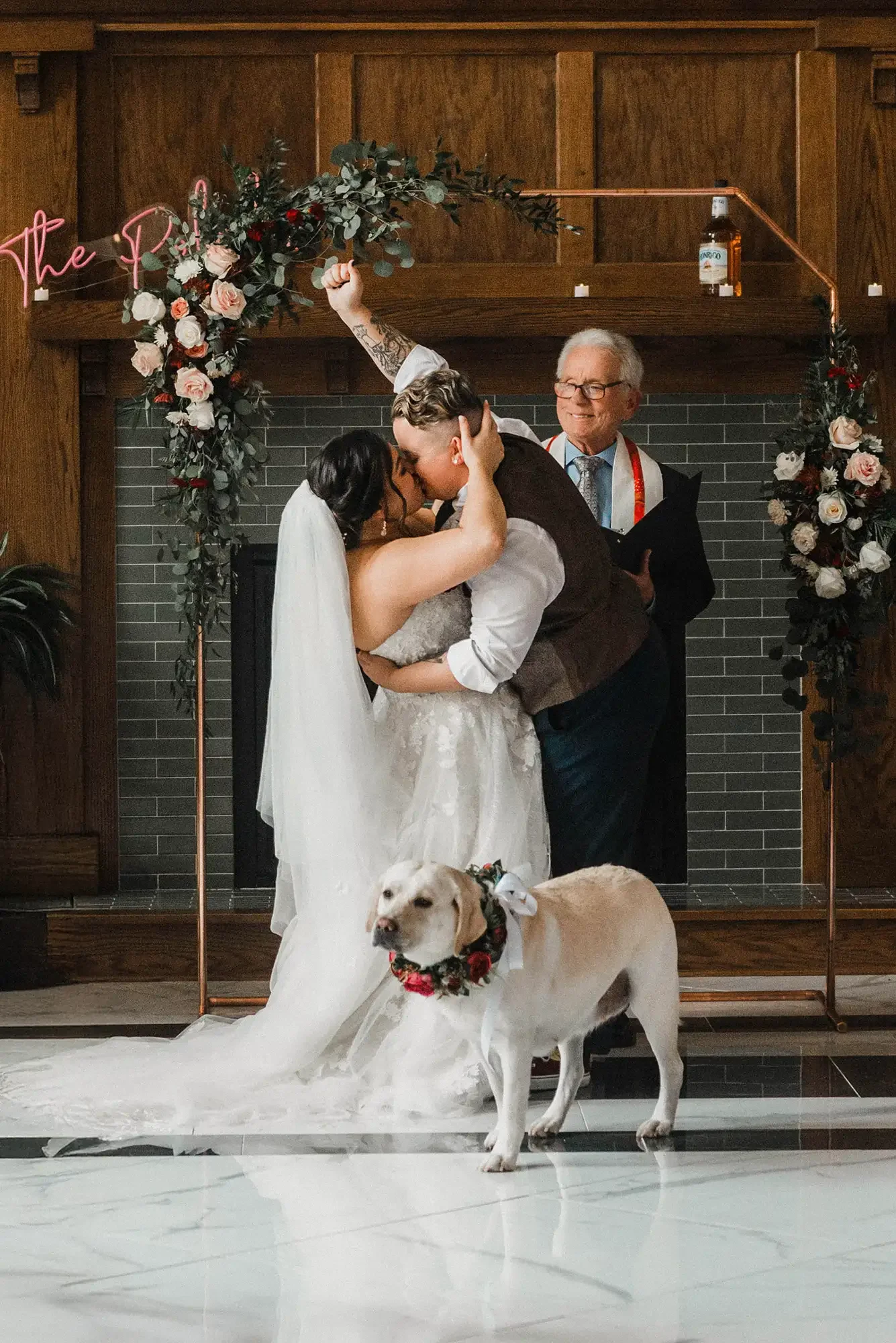 A couple kissing during their wedding ceremony with a dog wearing a flower collar in front of them. A person officiating the elopement in West Virginia.