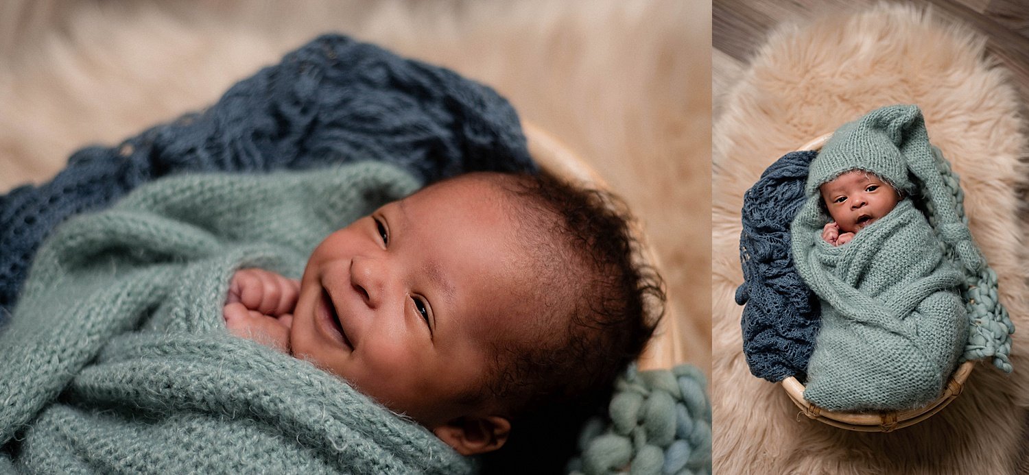 newborn smiling, dark skin, swaddled in blue knits with a long hat