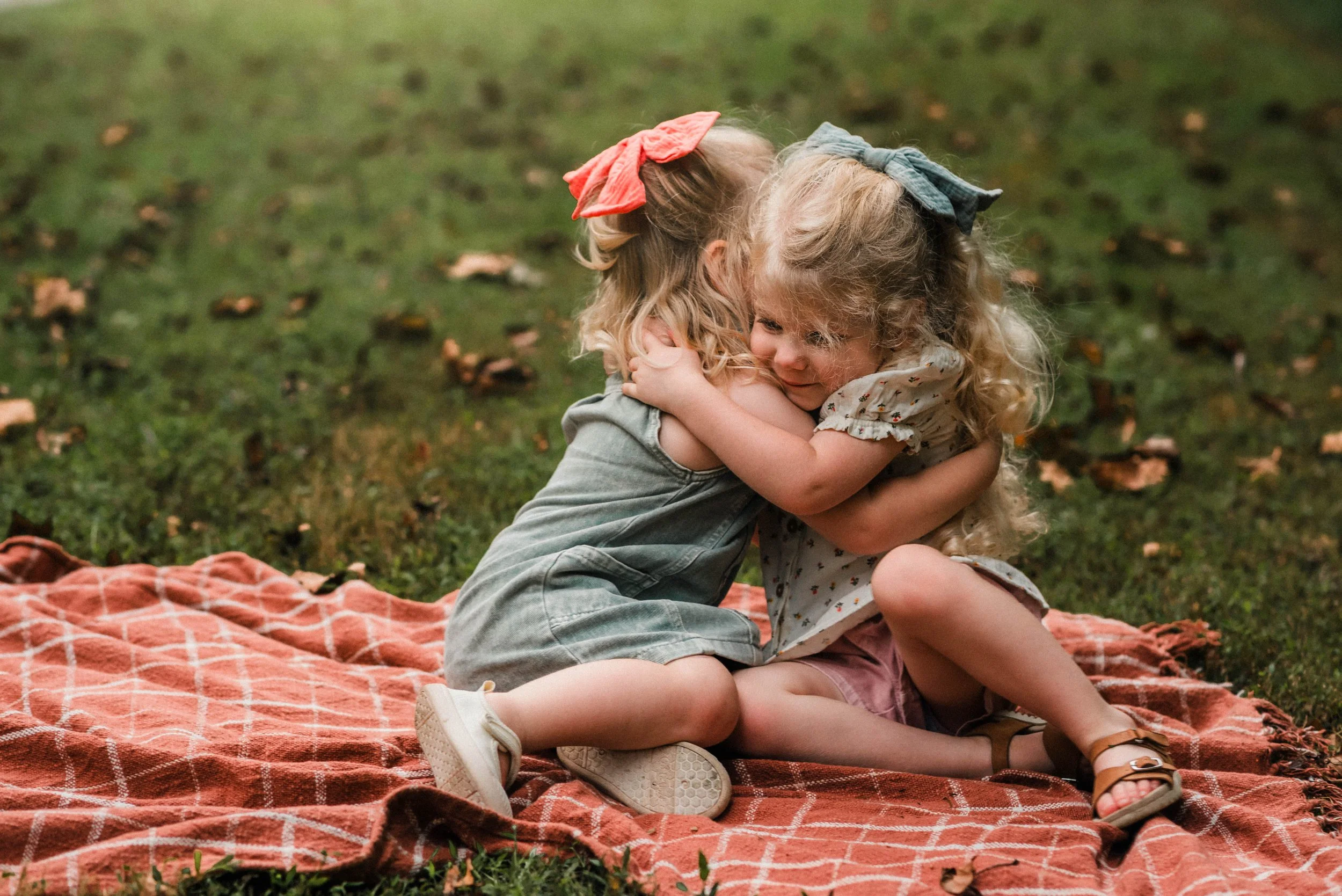 two young blonde girls hugging on a blanket in cedar creek park for their family's fall mini session
