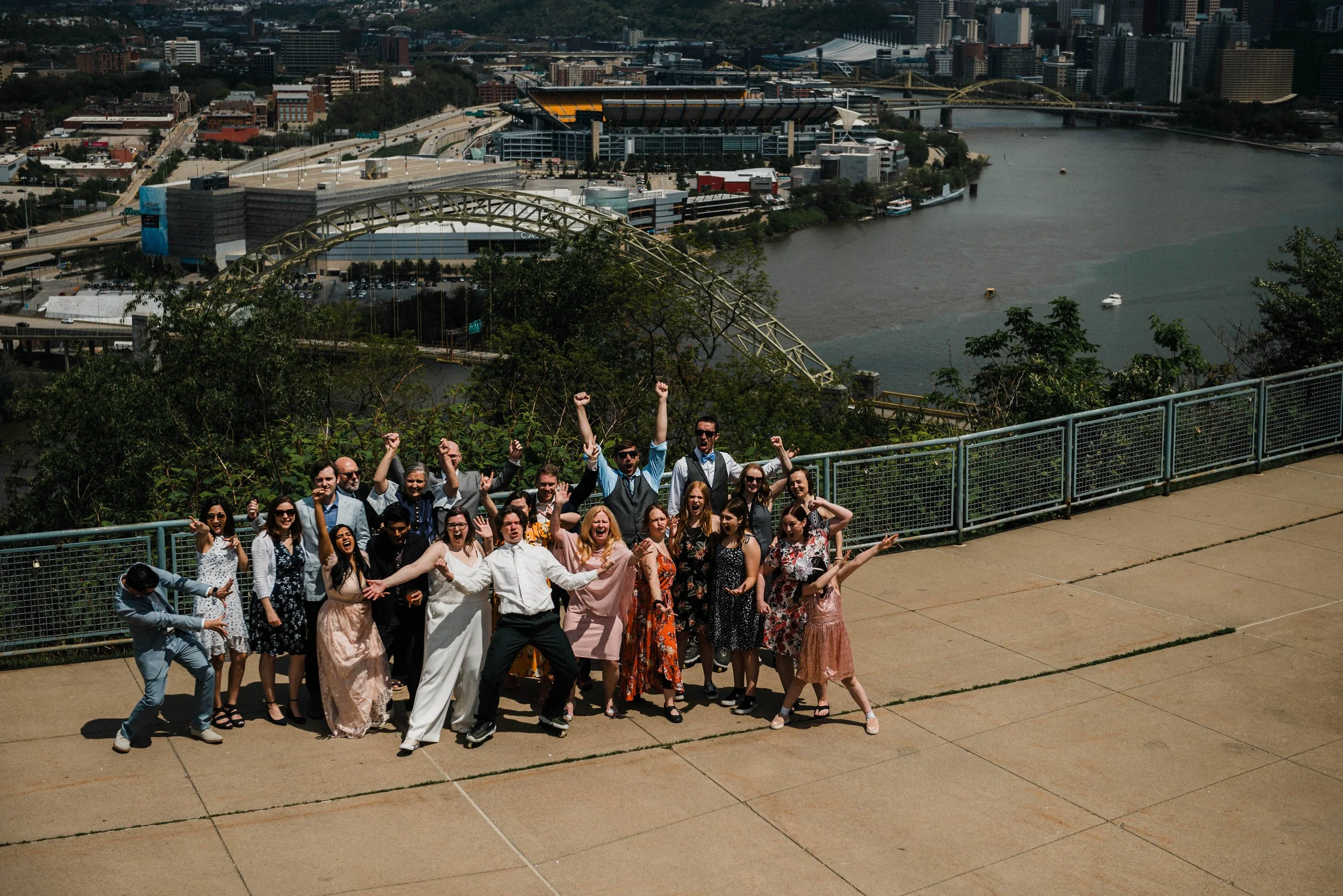 every guest at the wedding pose with the bride and groom at their west end overlook elopement, the city of Pittsburgh is visible behind them