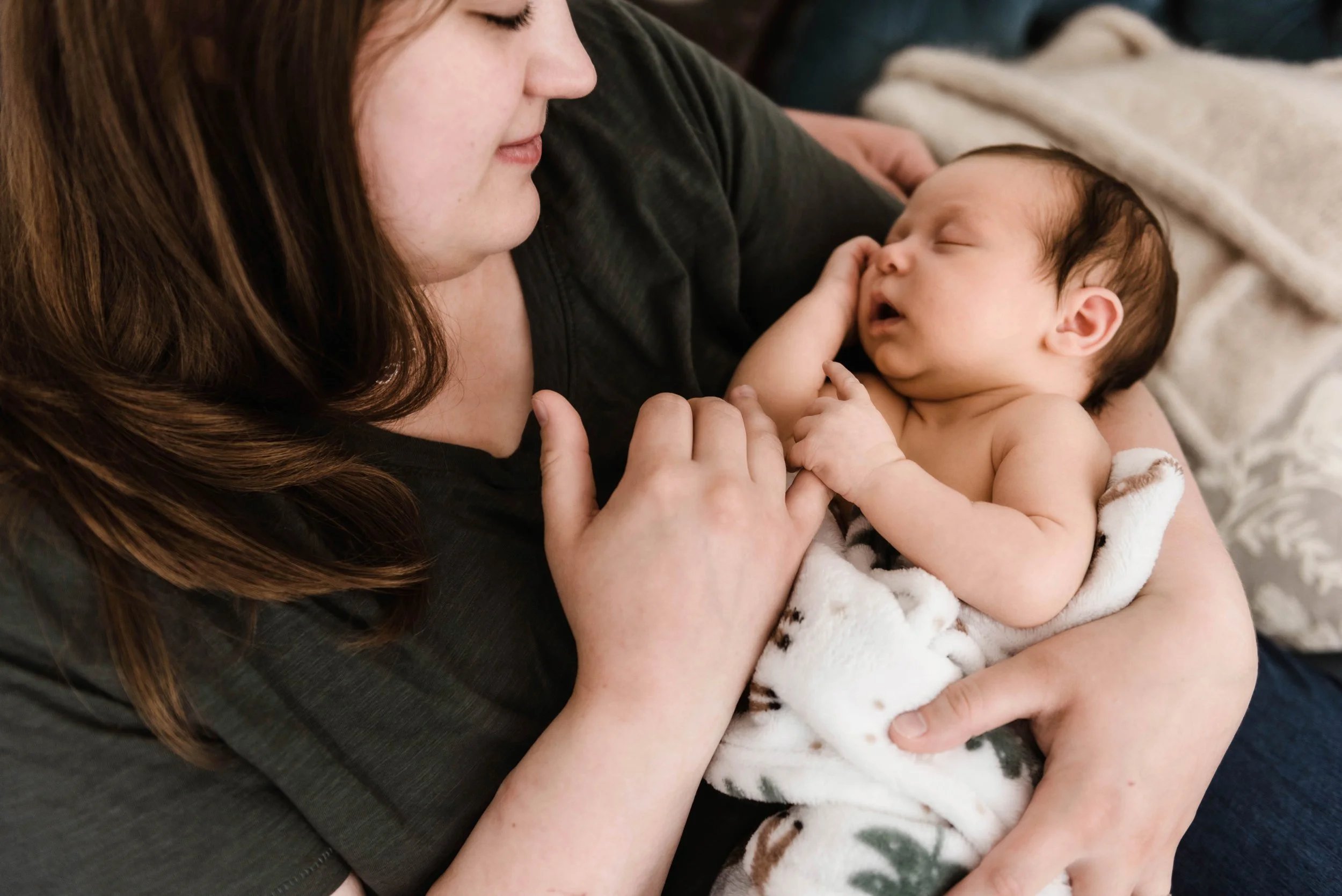 A woman holding a sleeping baby wrapped in a blanket. Studio newborn portrait, Uniontown PA.