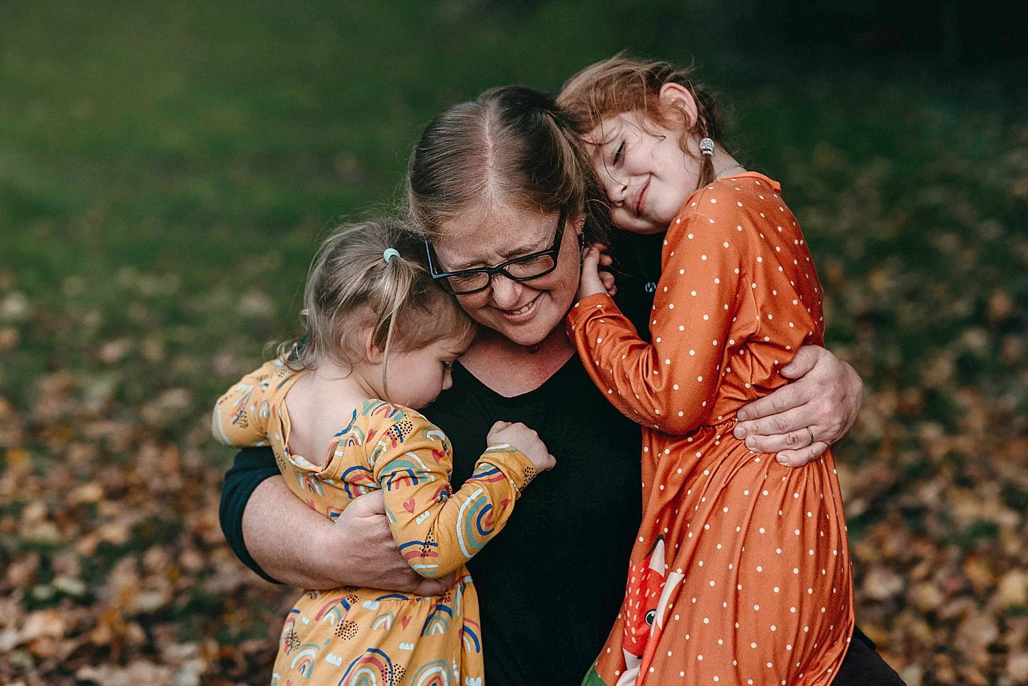 two young girls hug their mom at their portrait session at mingo creek park