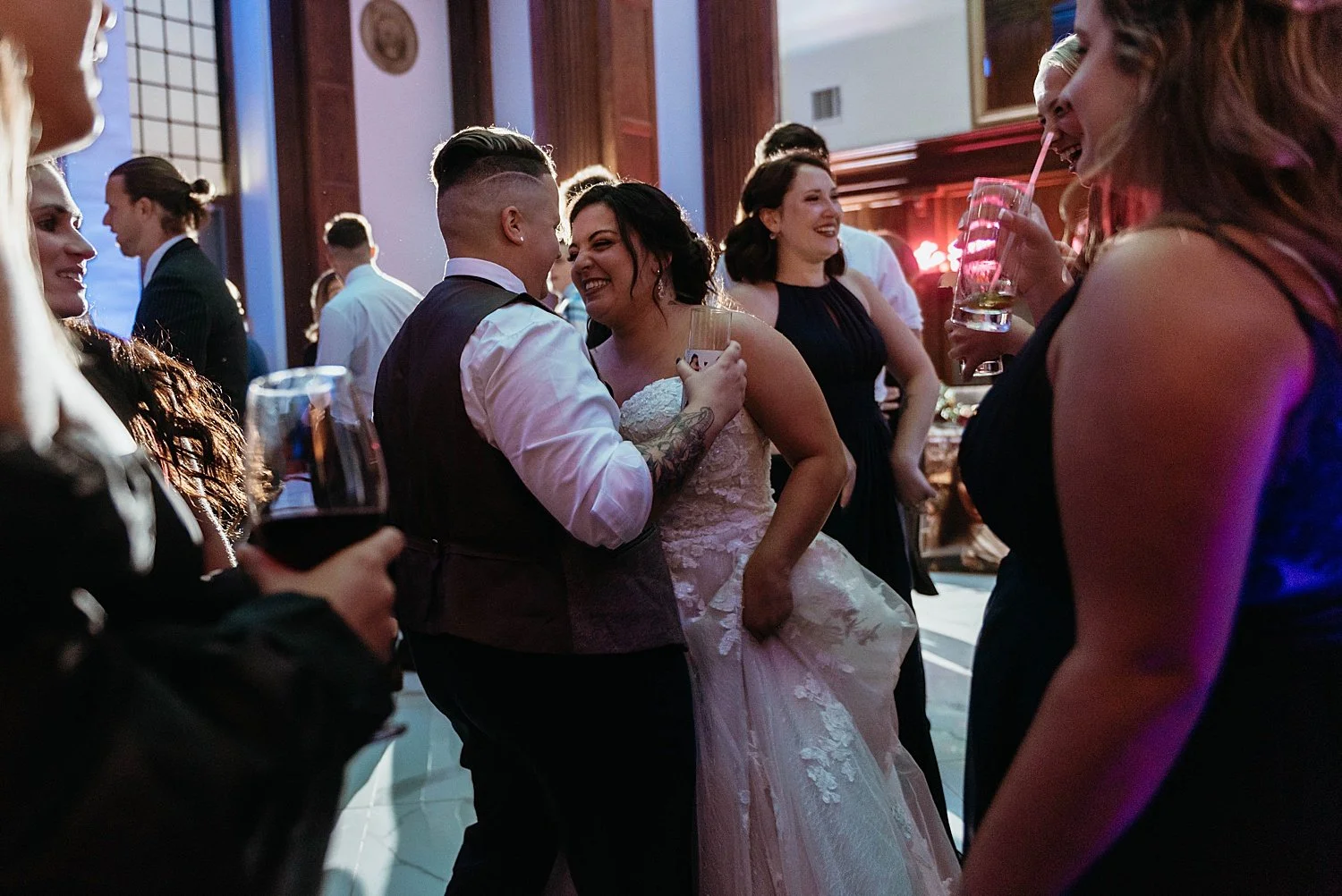 Bride and groom are dancing close together at the reception, groom is holding a drink
