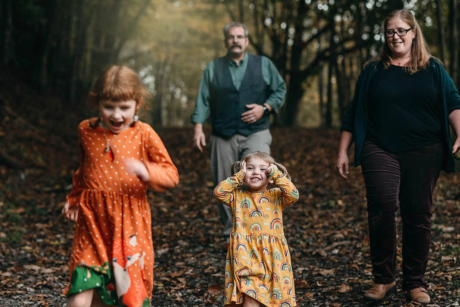 a family of four walks down a forest path in the fall at mingo creek park in finleyville, pa