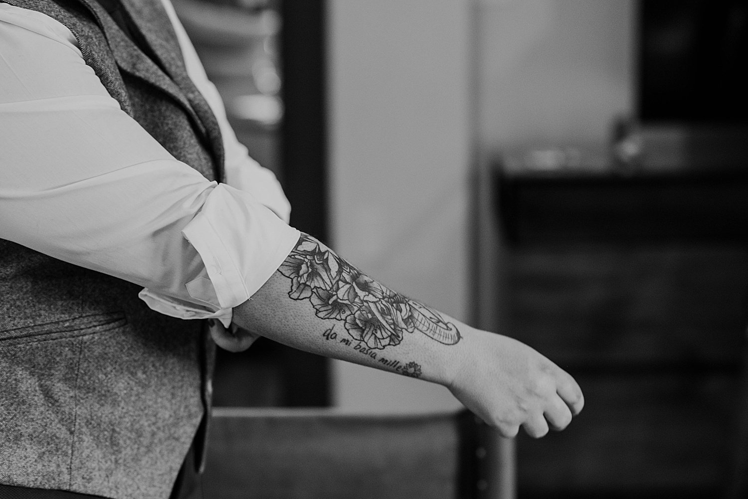 a clsoe up of the groom's tattoo which features flowers and the phrase da mi basia mille, Latin for "give me a thousand kisses"
