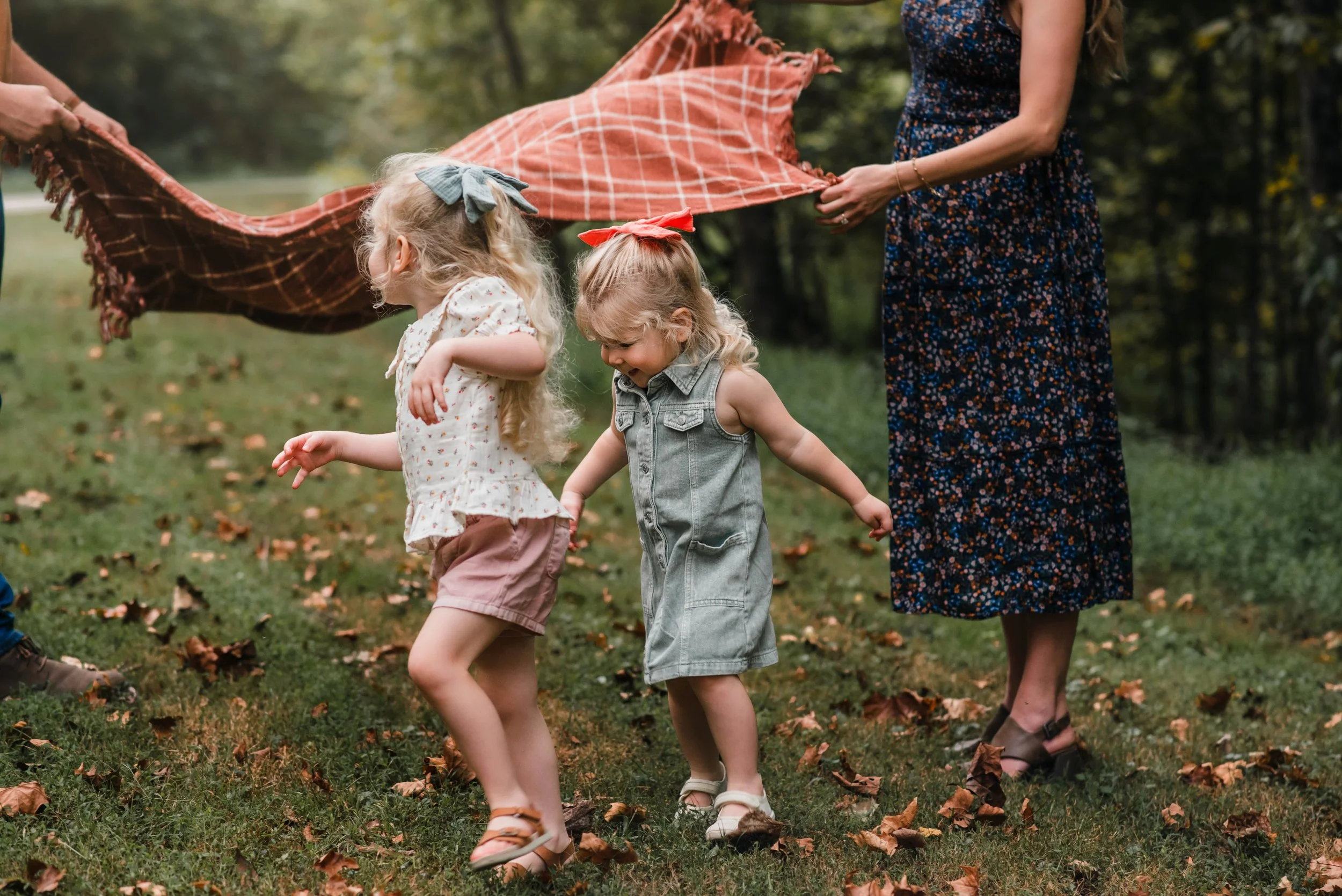 little girls running under a blanket that their parents are tossing