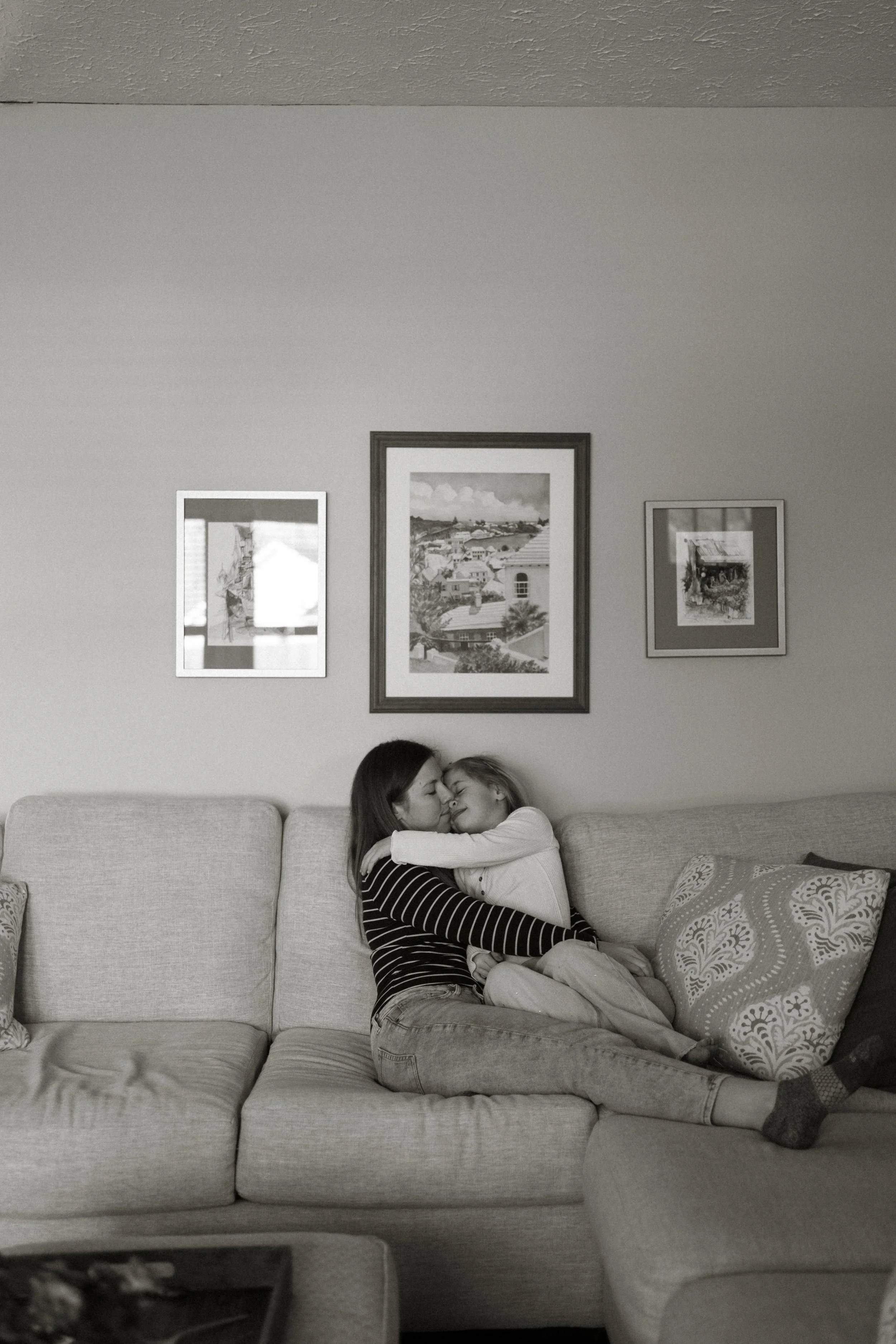 Mother and young daughter hugging on the couch, black and white photo