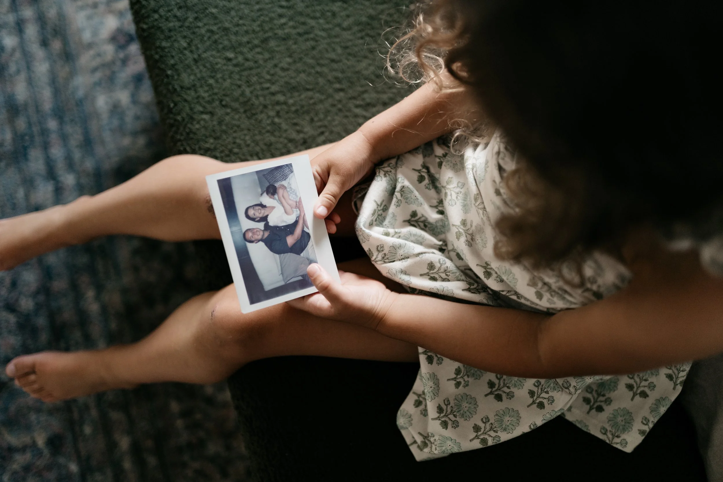 Daughter holding Instax instant photo of parents with newborn sibling