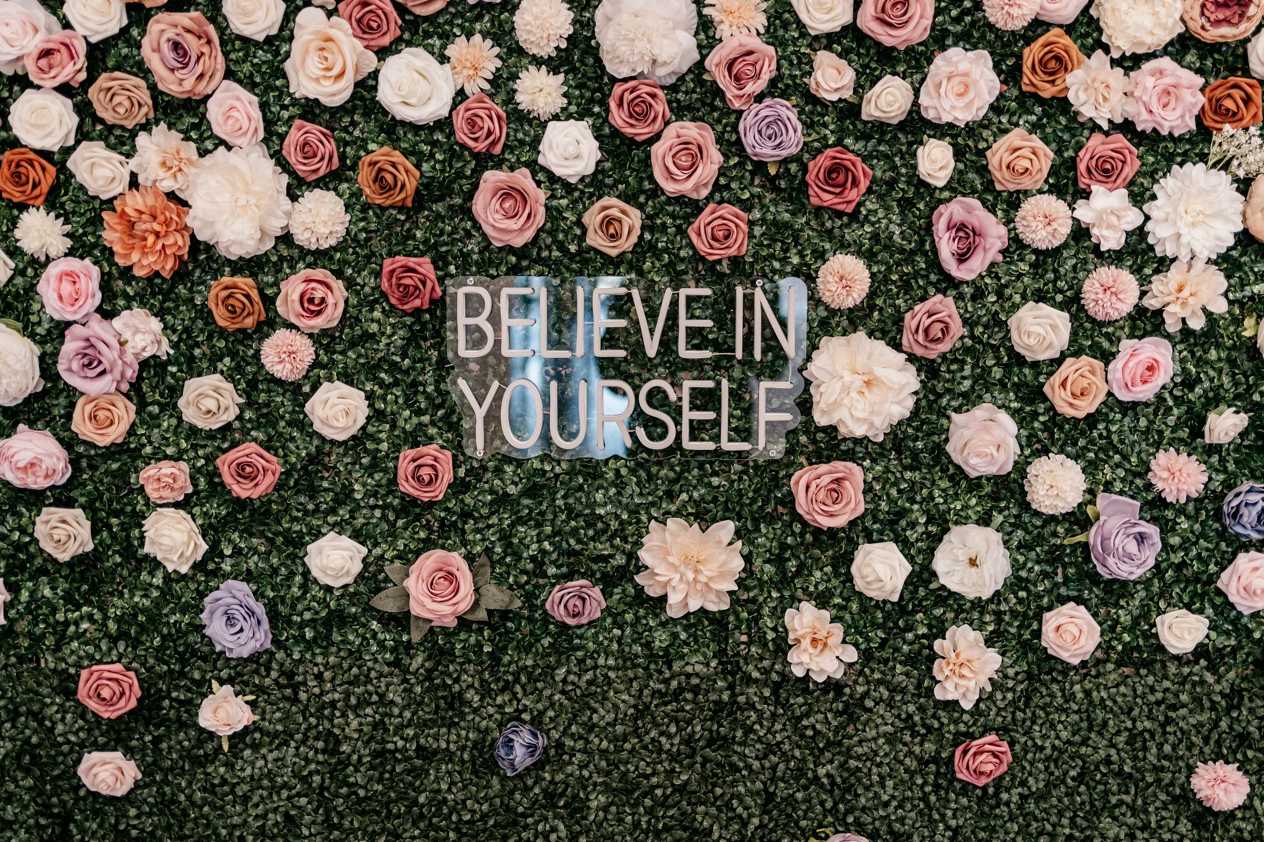 picture of flower wall with sign that says 'believe in yourself'