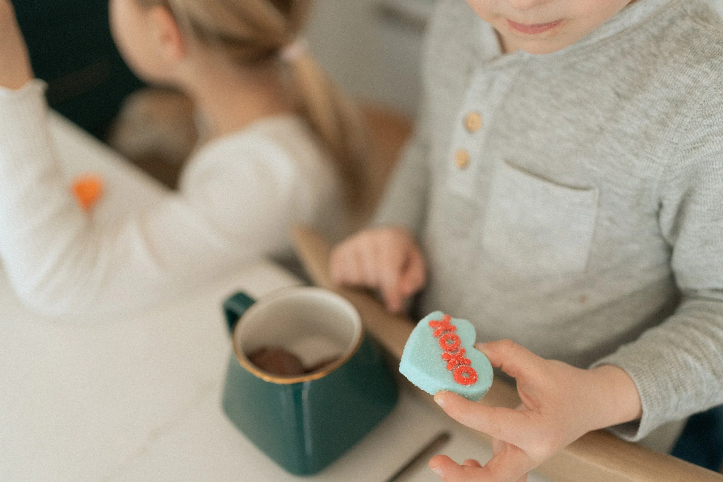 Young boy drinking hot chocolate, holding a heart marshmallow