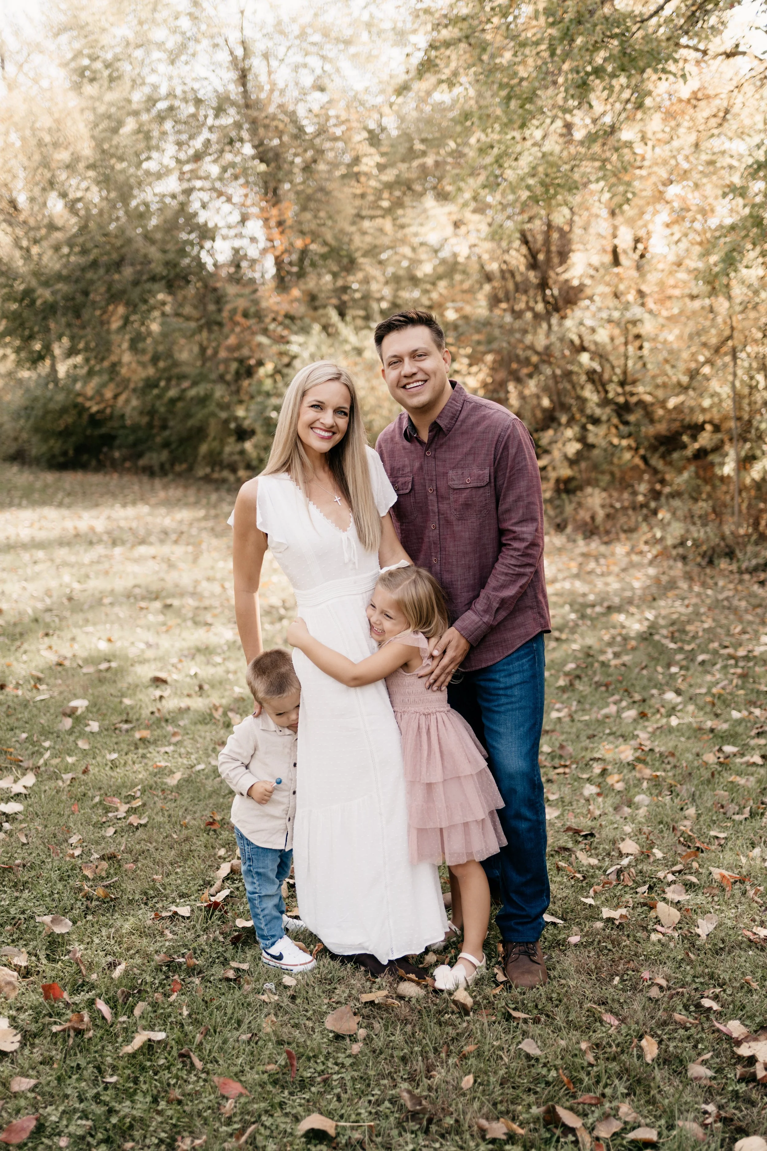 Father, mother, young daughter and young son, standing together smiling and hugging