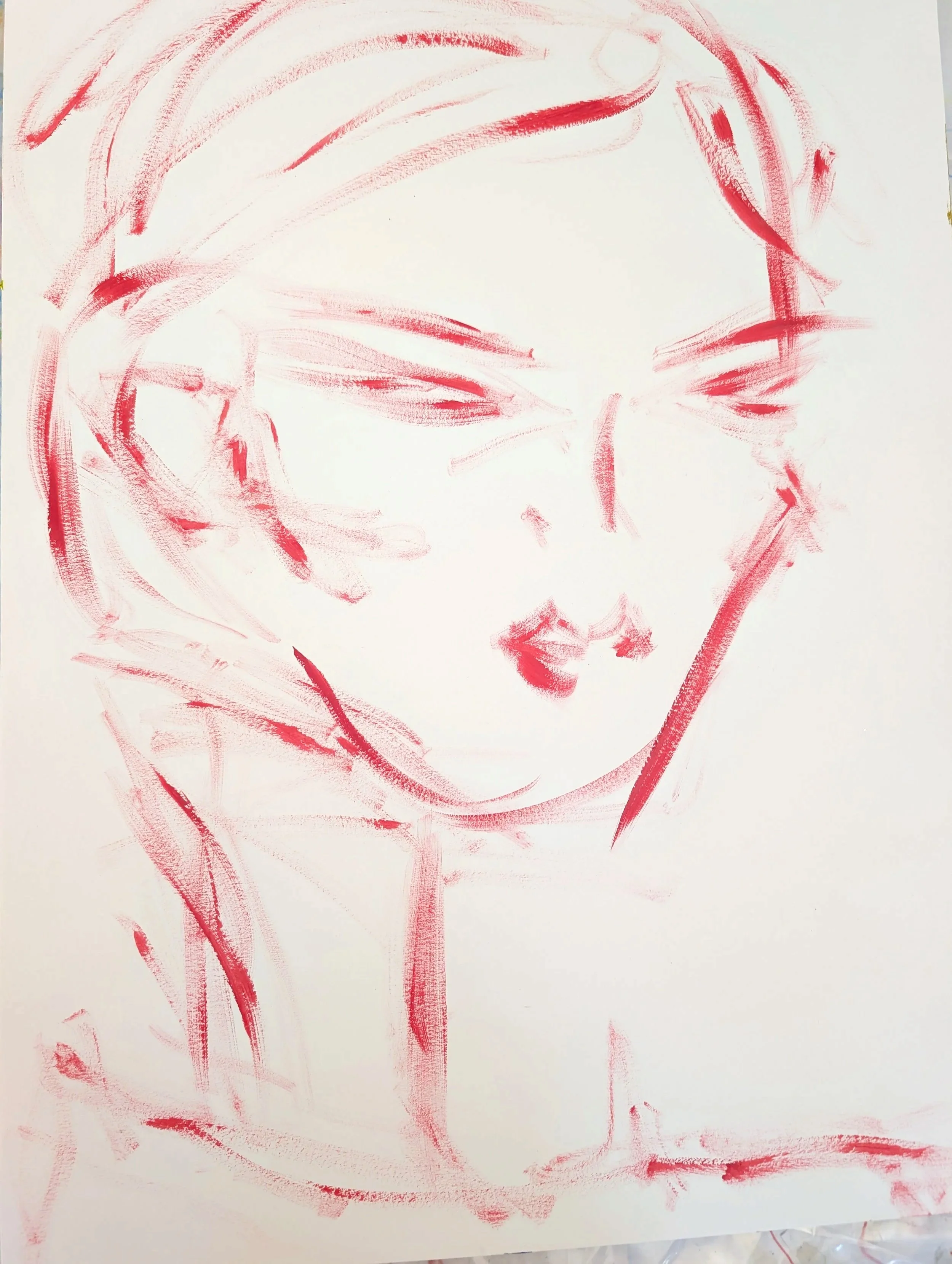 Child's drawing of a face with red lines on white paper.