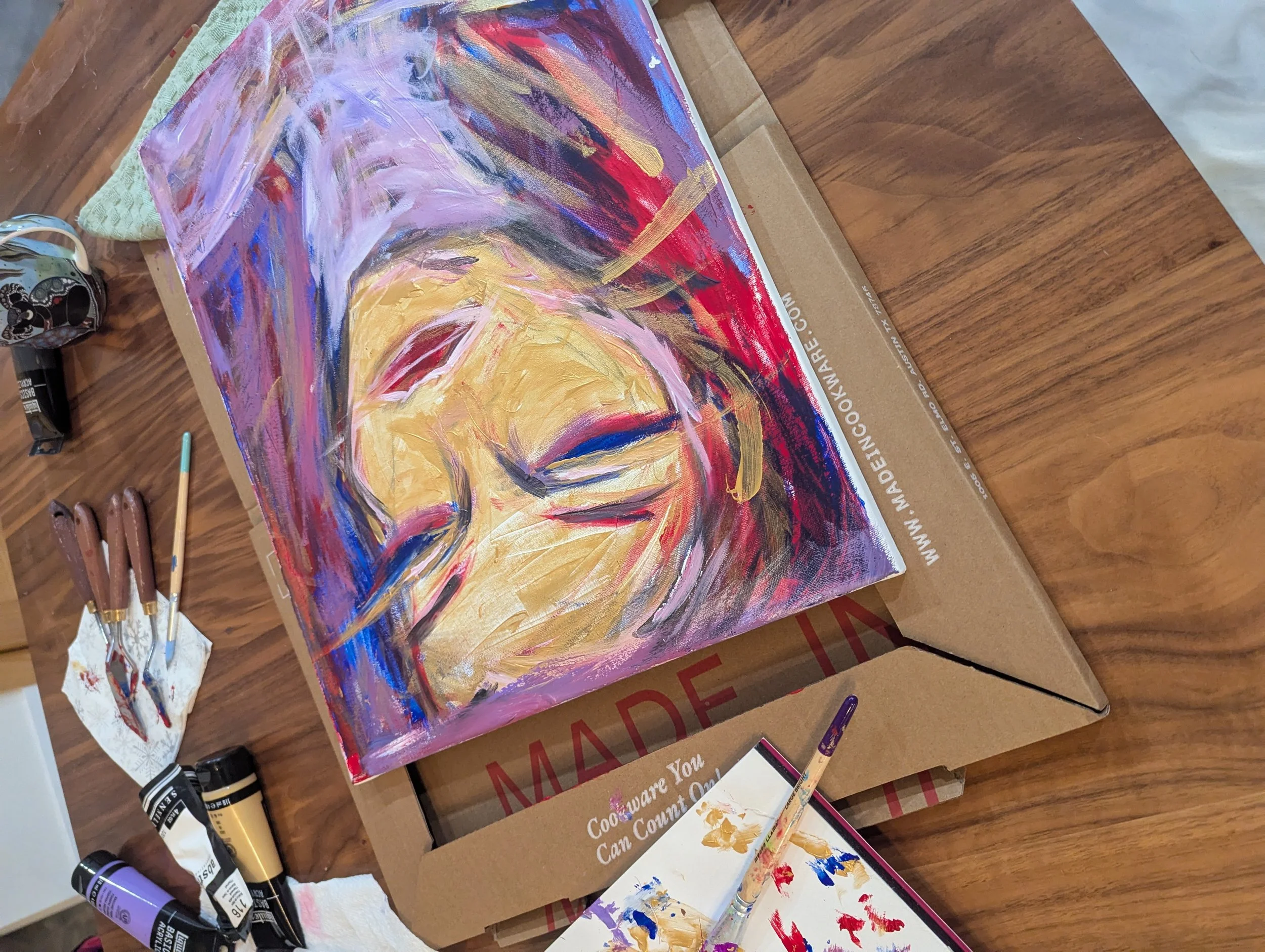 An abstract portrait painting of a woman with flowing hair, painted with bold brushstrokes in pink, purple, red, black, and gold on a canvas.