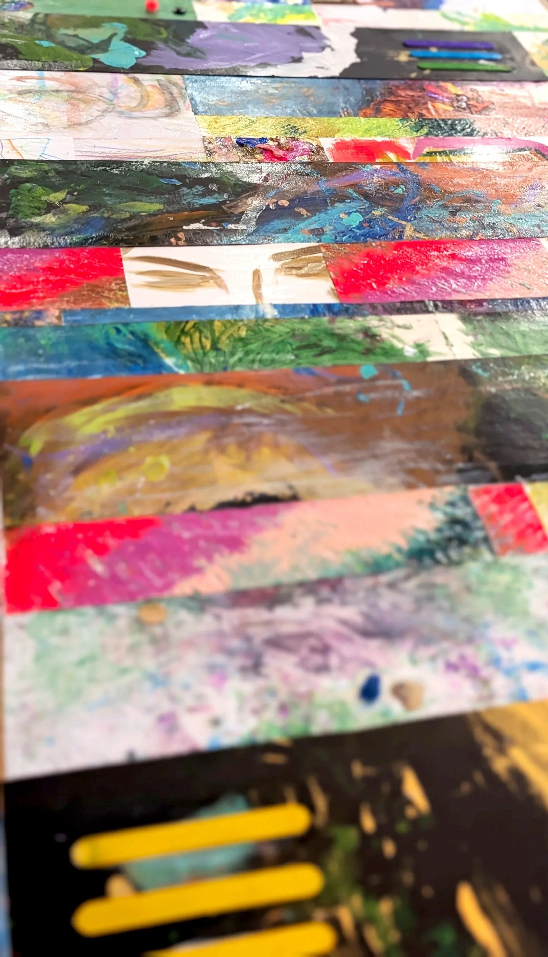 Close-up of colorful, abstract painted strips on paper, with various shades of green, red, blue, yellow, and purple, showing brush strokes and layered textures.