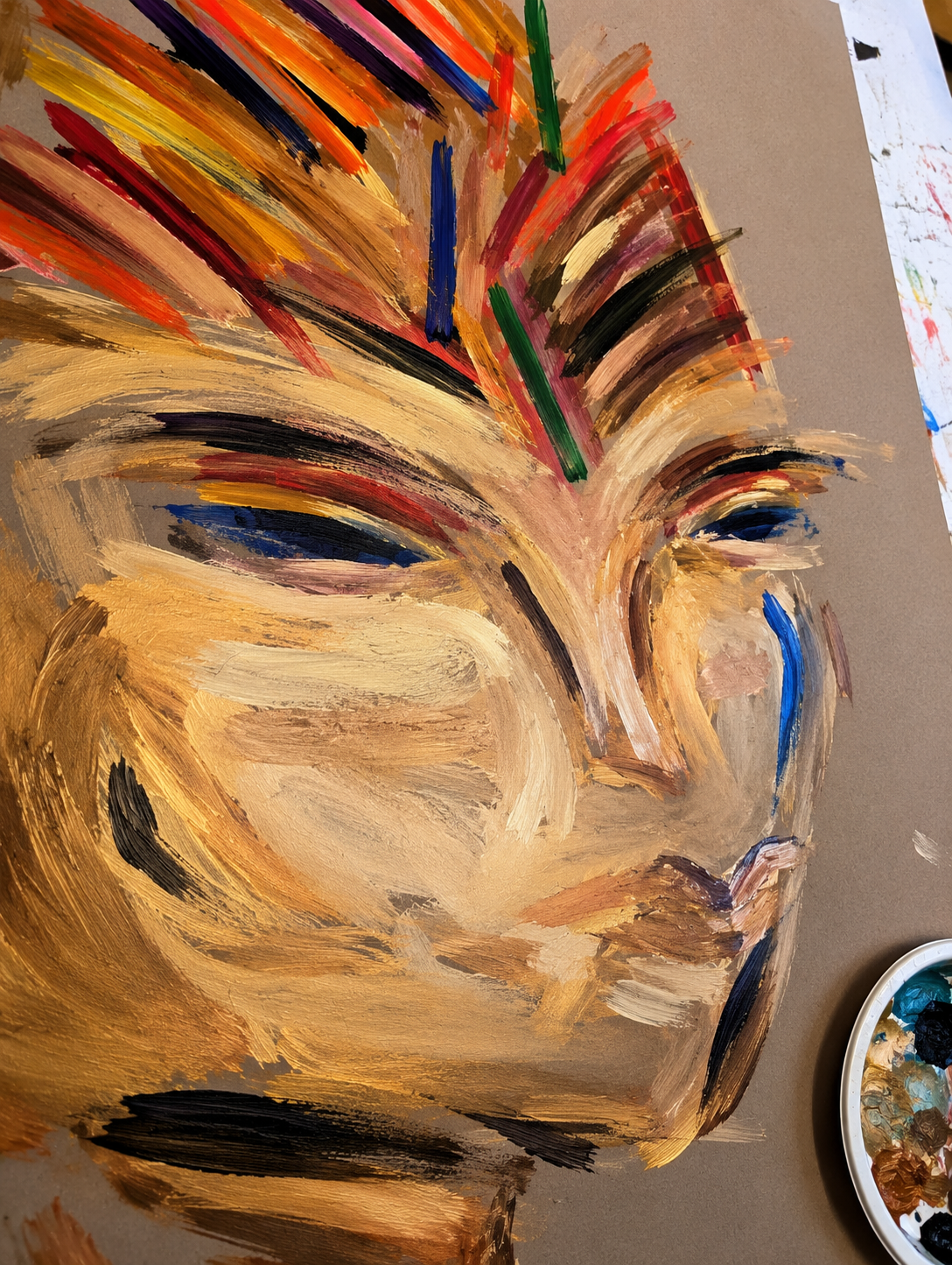 Close-up of a painted open book with colorful brush strokes and painted popsicle sticks attached, creating an abstract art piece.