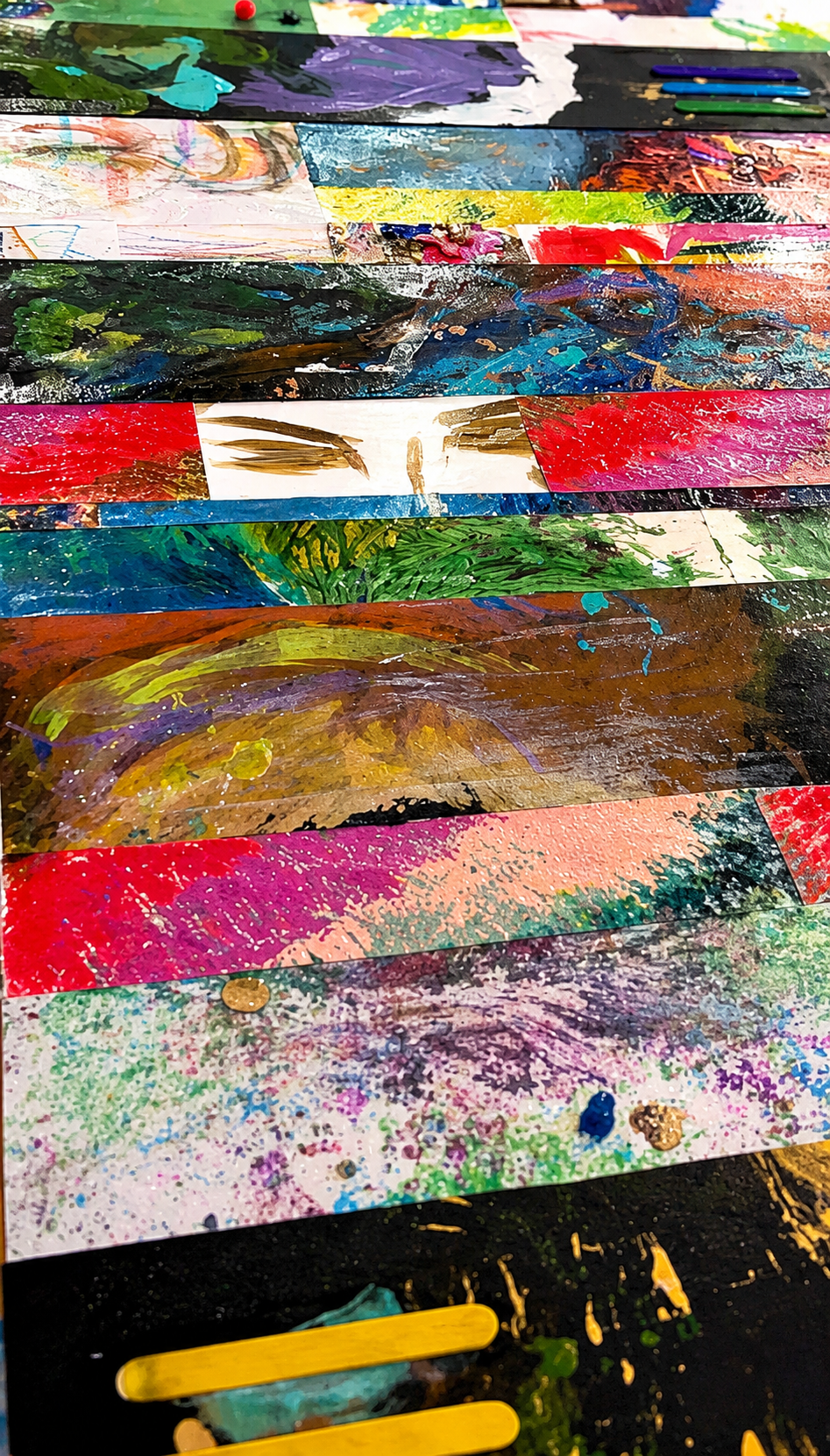 Close-up of colorful, abstract painted strips on paper, with various shades of green, red, blue, yellow, and purple, showing brush strokes and layered textures.