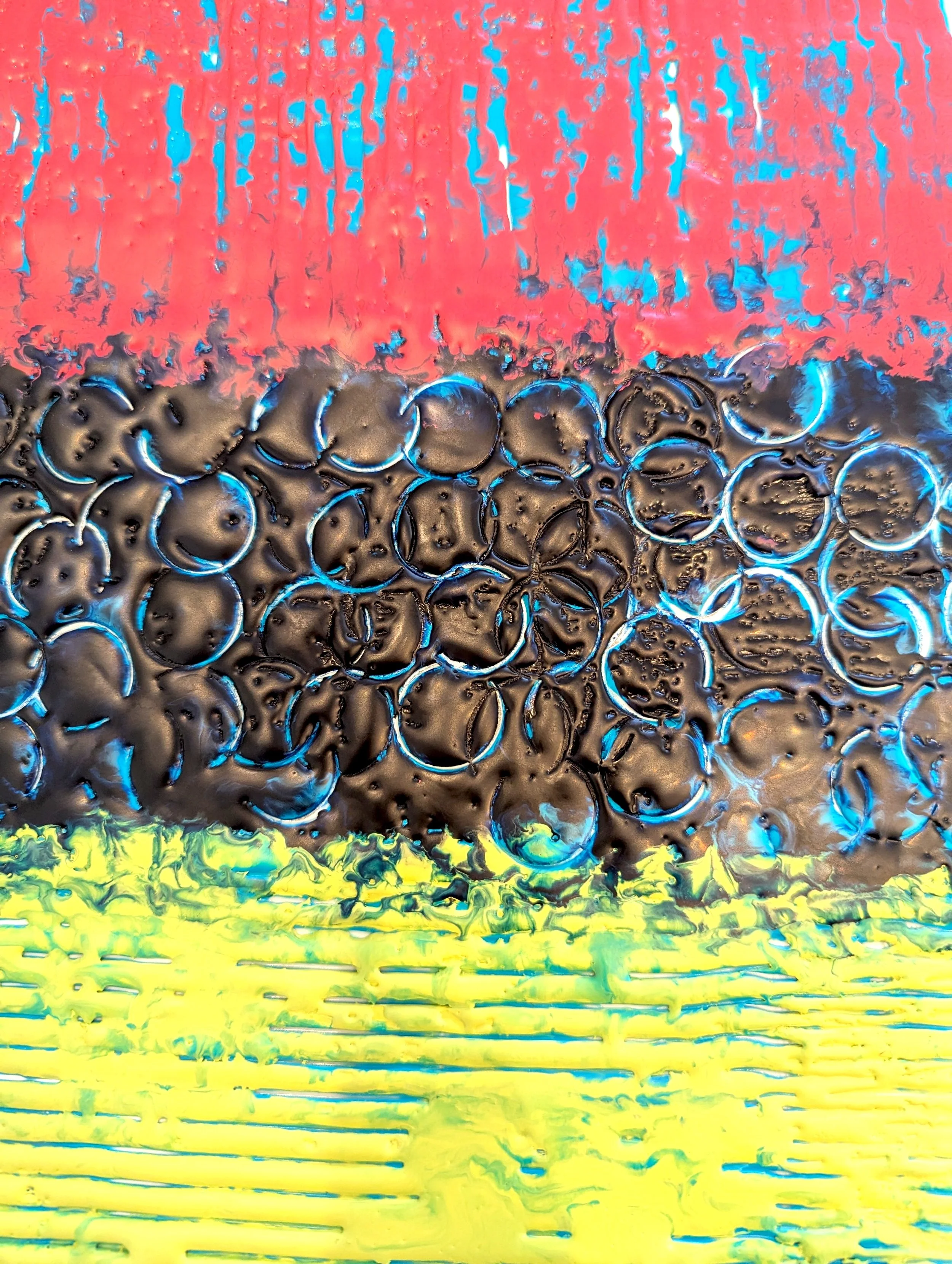 Abstract artwork with three horizontal sections: the top section is red with blue streaks, the middle section is black with numerous blue rings and bubbles, and the bottom section is yellow with green and blue streaks.