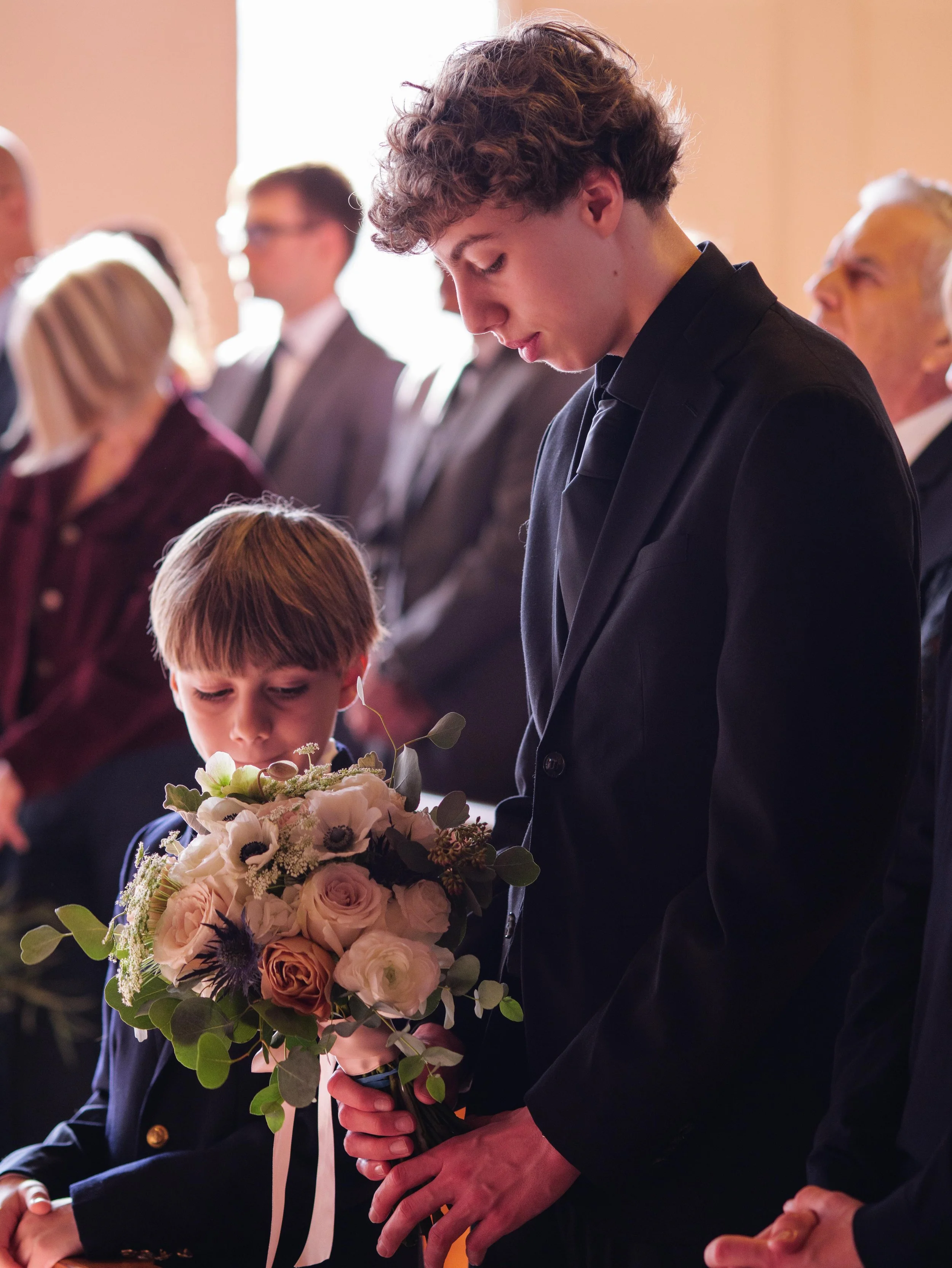 A young man and a boy holding a bouquet of flowers during a formal ceremony or event.