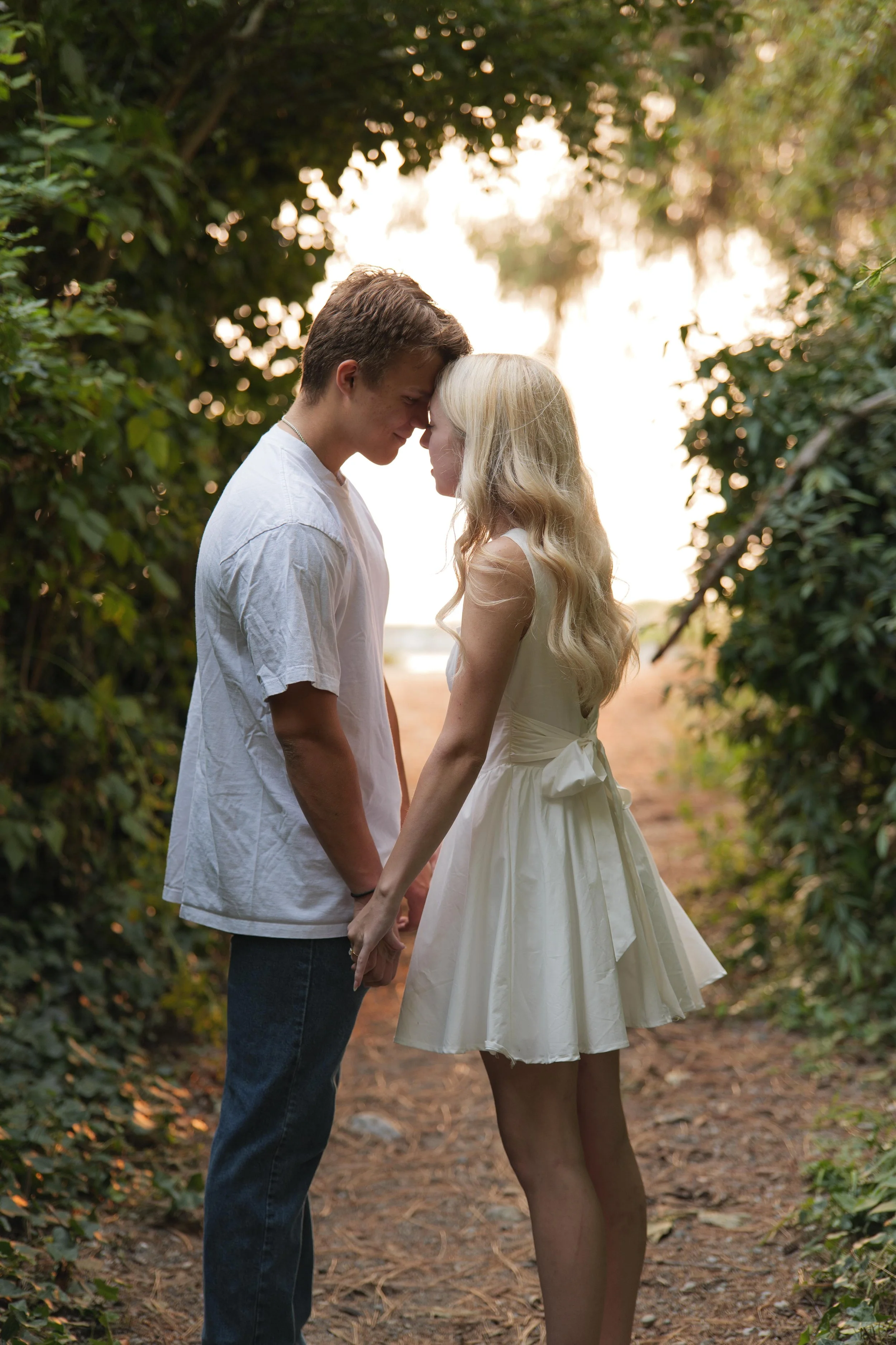 Kiarrah and Julian facing each other beneath a tree during their West Vancouver engagement photography session.