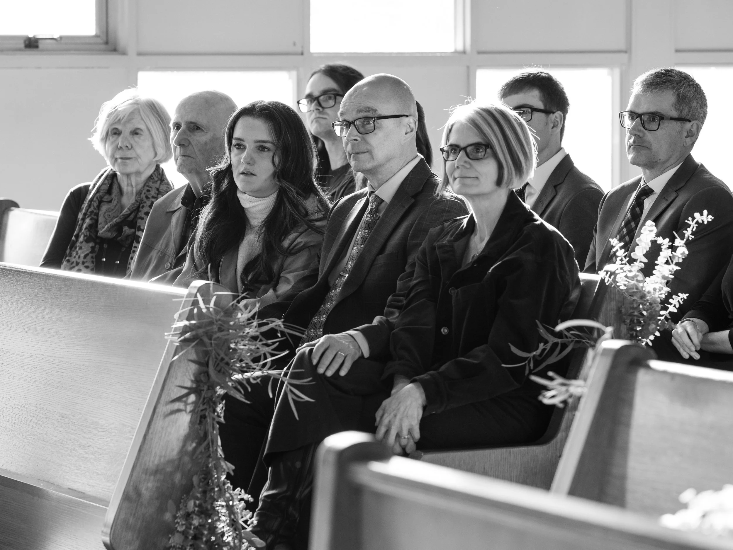 A group of people sitting in pews in a church or auditorium, attentively listening to an event or speaker.