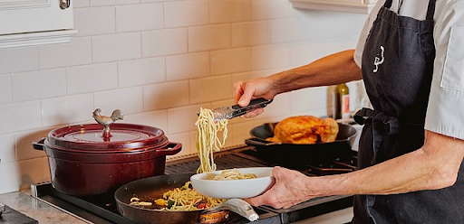 Chef leading an interactive cooking class at home in Nantucket, MA while serving freshly made pasta.