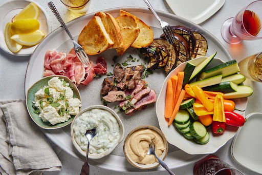 Interactive cooking class in Nantucket, MA featuring charcuterie, grilled steak, fresh vegetables, and homemade dips.