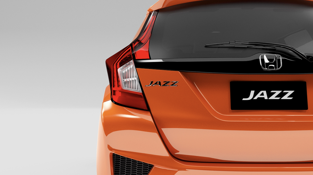 Rear view of an orange Honda Jazz car with badge and logo.