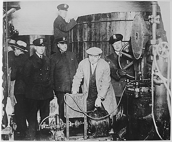 Group of men in early 20th-century uniforms and clothing operating machinery or equipment.