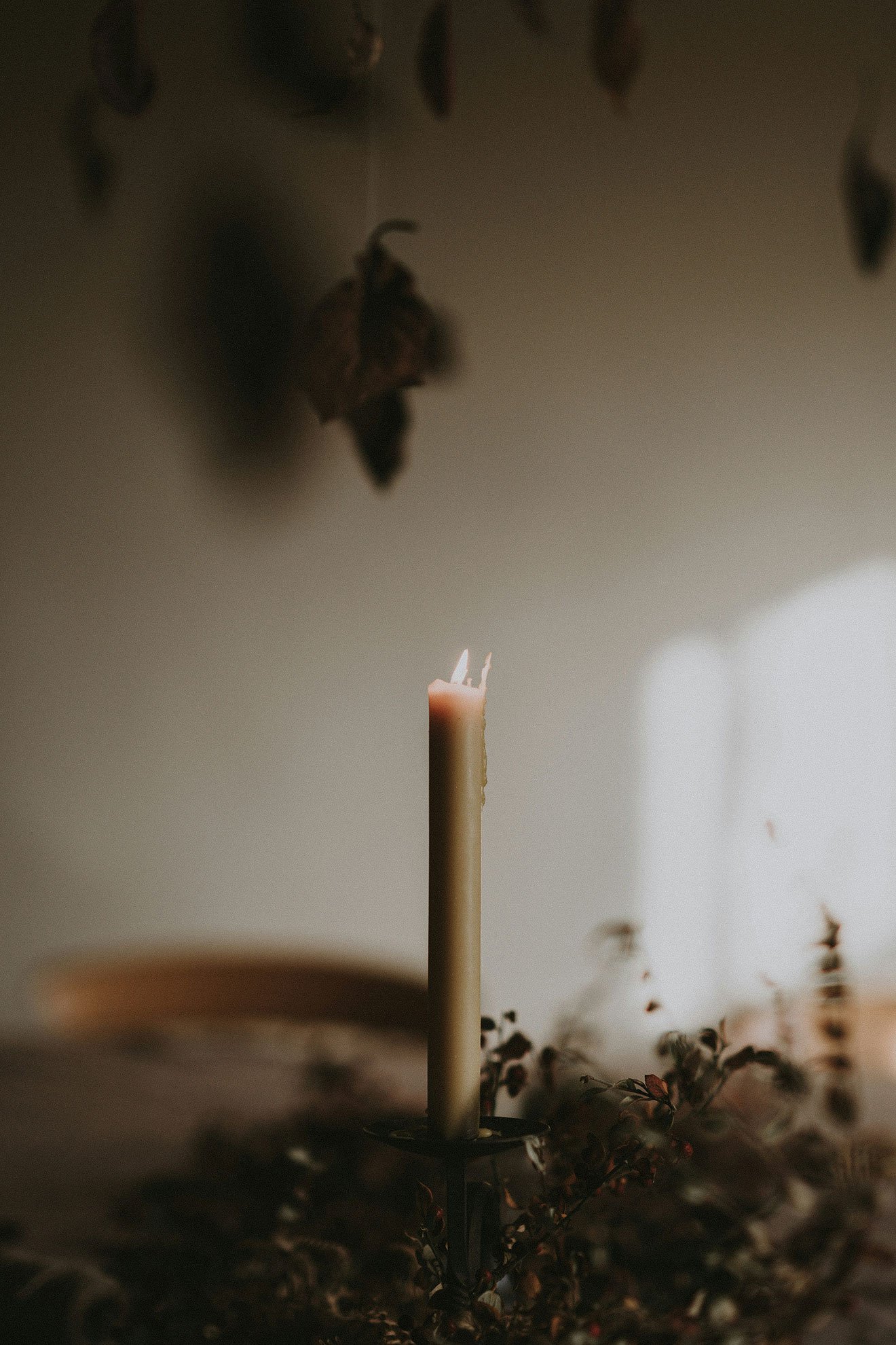Lit candle on a wooden table to celebrate Imbolc