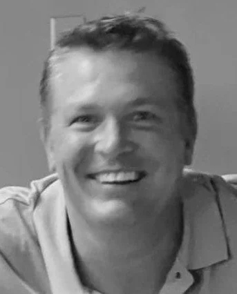 A smiling man with short hair in a casual shirt