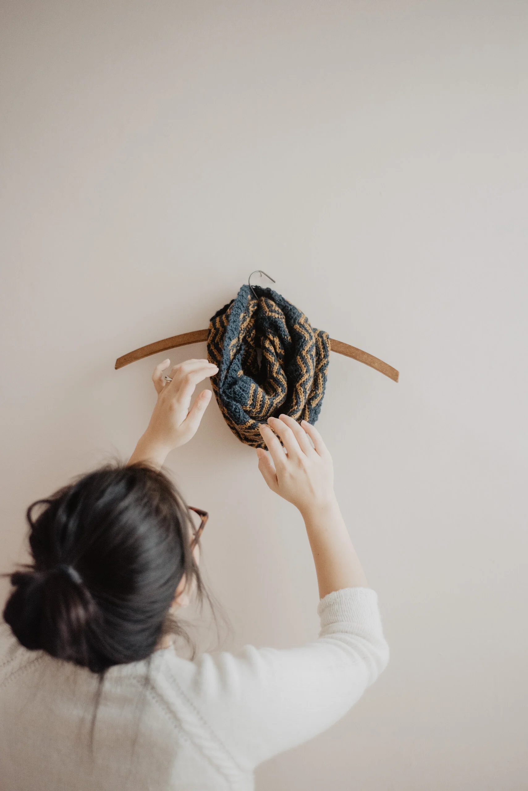 Woman arranging Tweel Infinity Scarf on a hanger