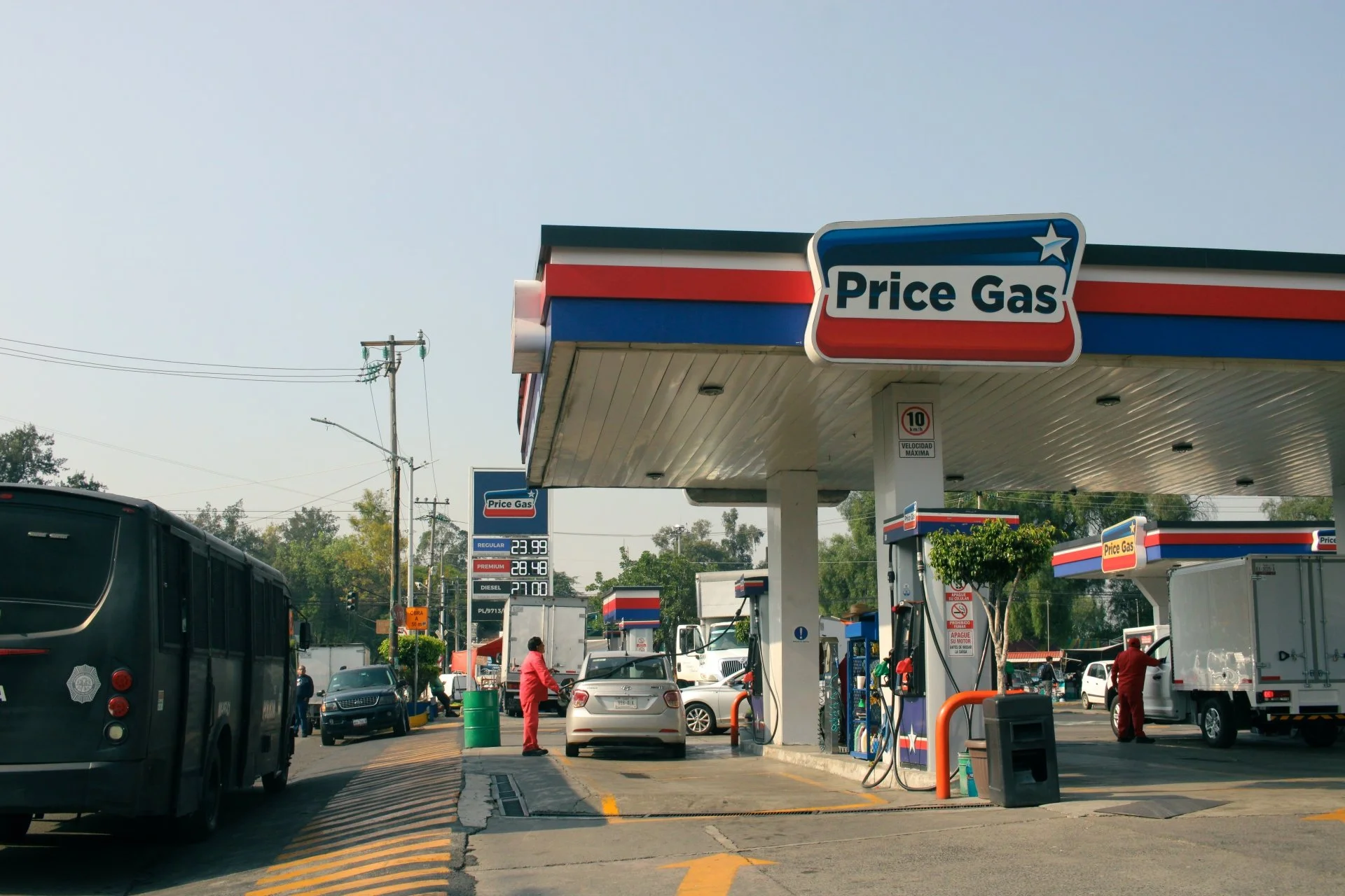 Price Gas station in Mexico with cars, trucks and workers refueling under the canopy.