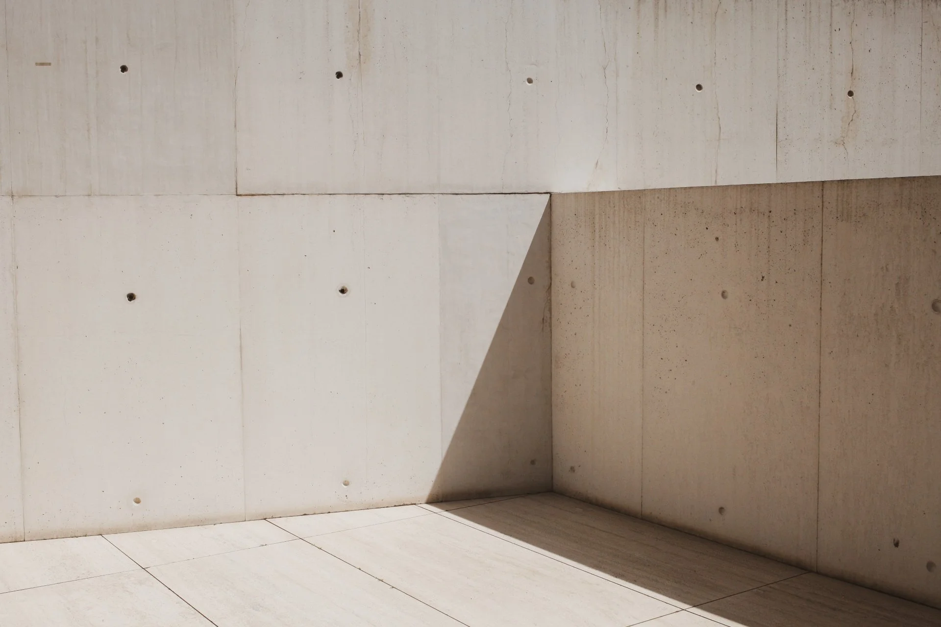 Empty beige marble corner with a shadow cast on the wall and floor.