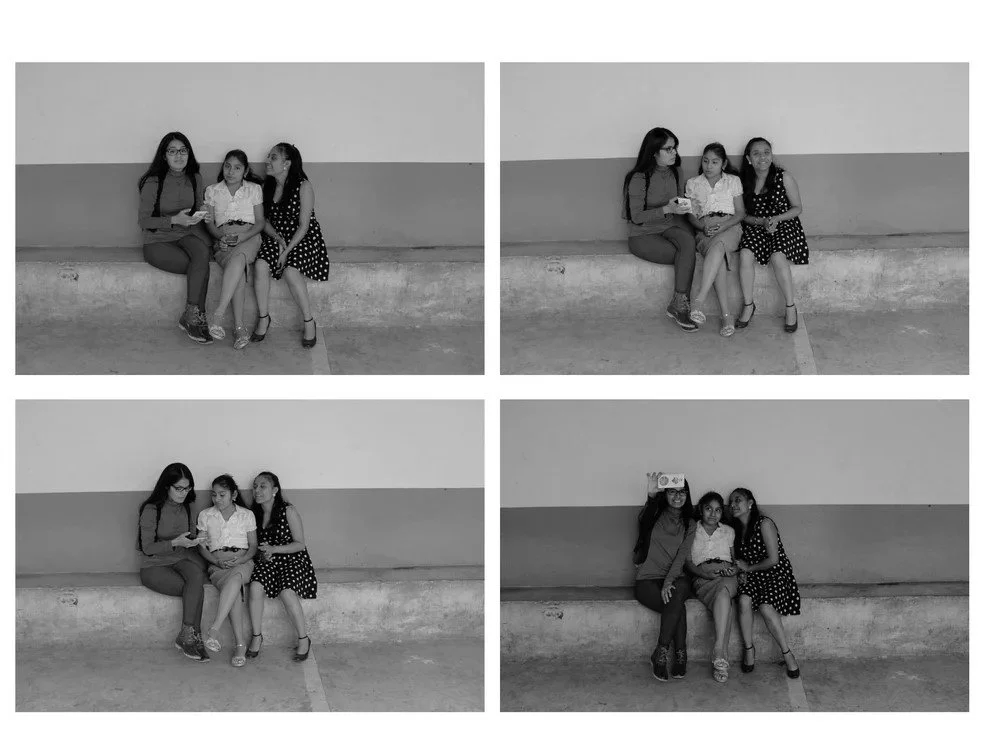 Four black-and-white photos of three girls sitting on a bench against a plain wall, taking turns posing, talking, and making gestures.