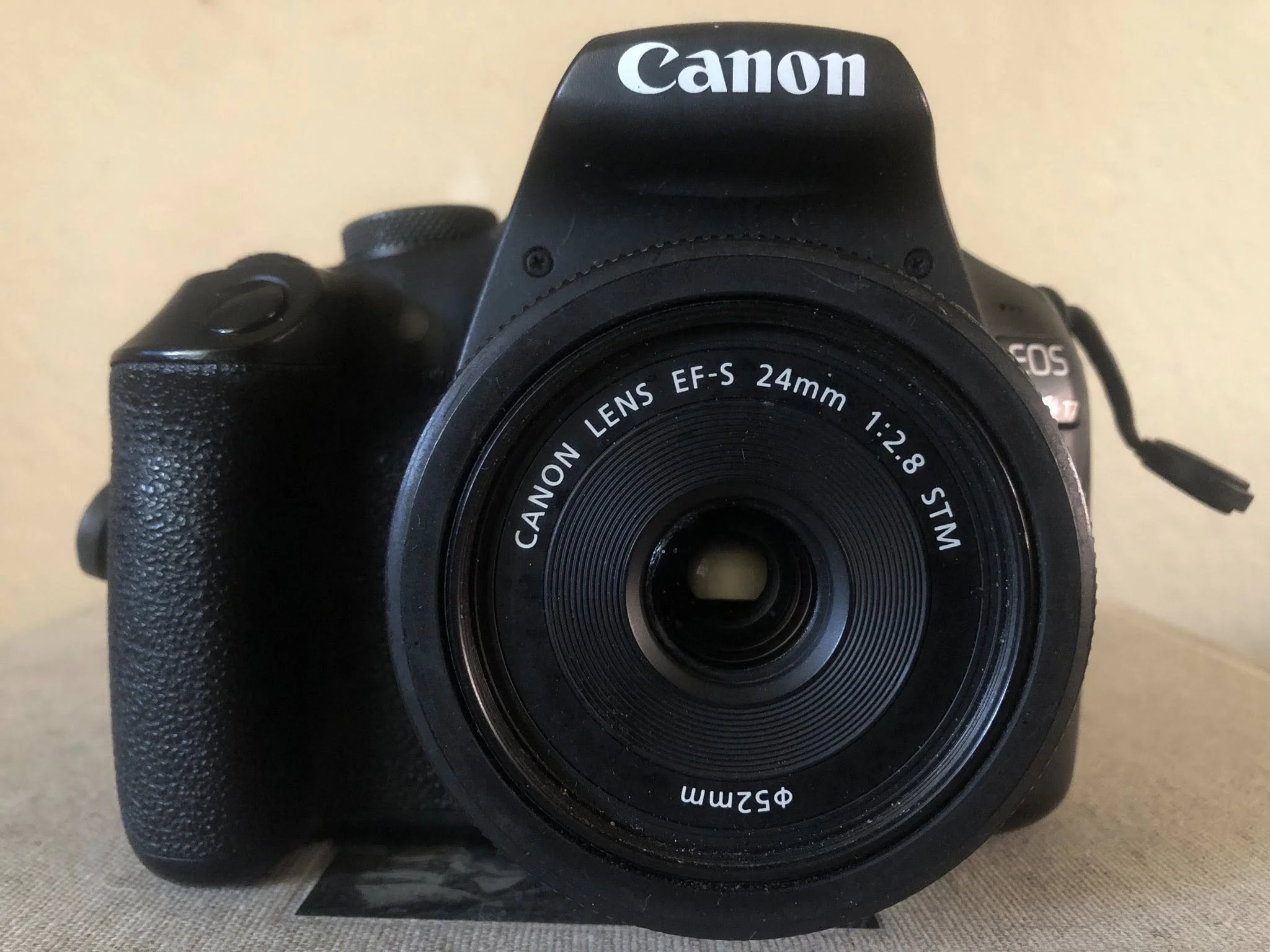 Close-up of a Canon digital camera with a 24mm lens, focusing on the brand name and lens markings.