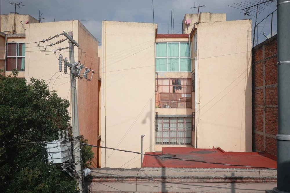 A view of several residential buildings with electrical wiring and utility poles in an urban setting.
