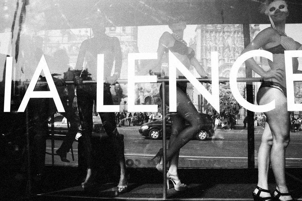 Display window with mannequins dressed in lingerie and masks, with the word 'ALLIANCE' partially visible on the glass.