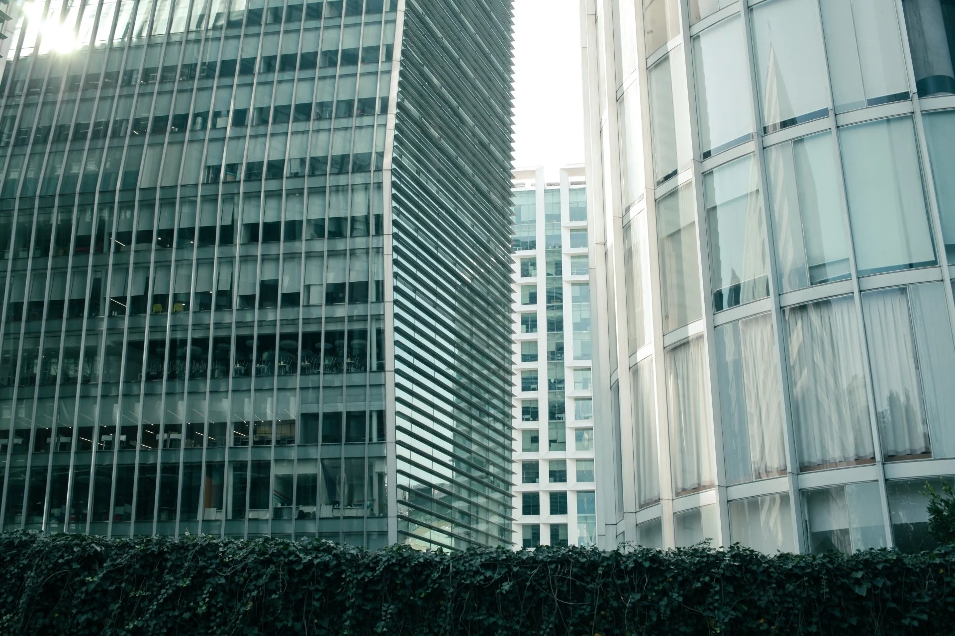 Multiple modern glass skyscrapers with reflective windows in an urban cityscape.